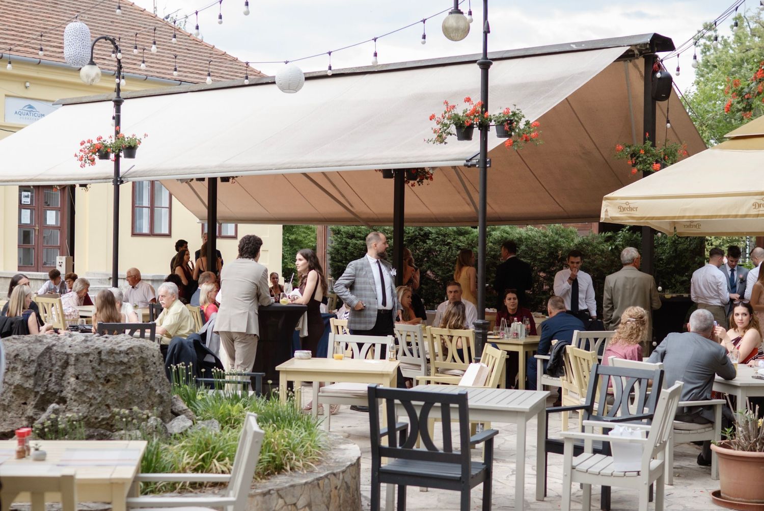 Guests dining outdoors under elegant cream awnings at a European wedding reception venue.