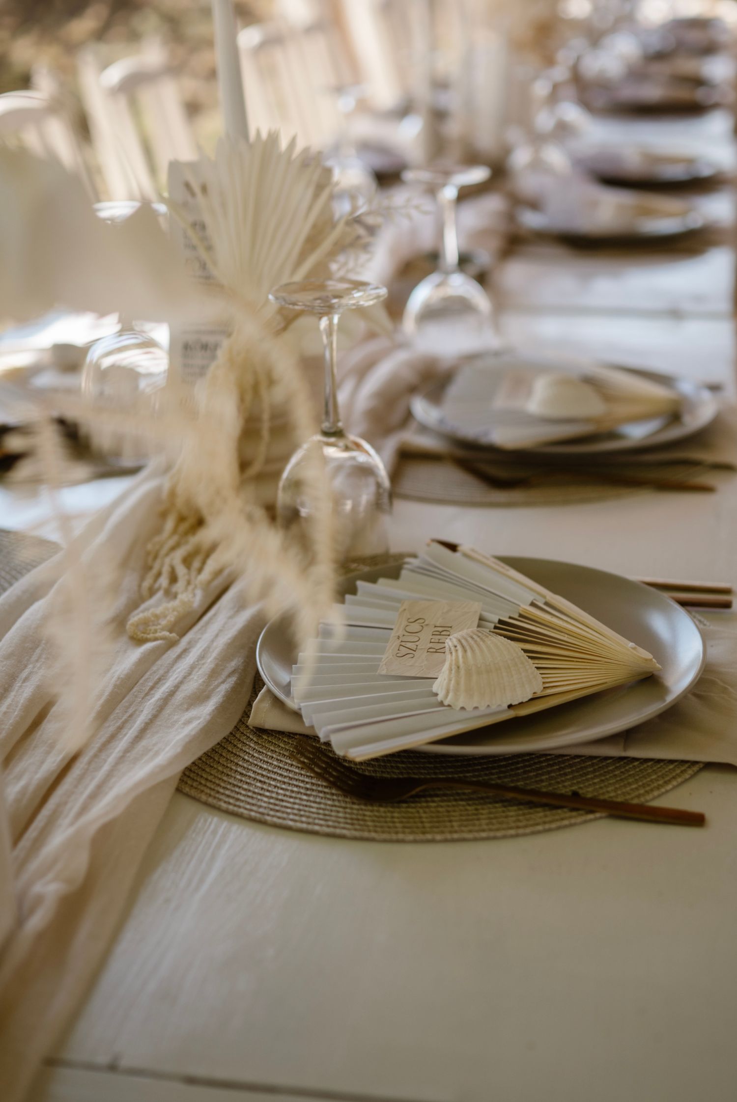 Elegant boho wedding table setting with pampas grass, fan place cards, and neutral tones.