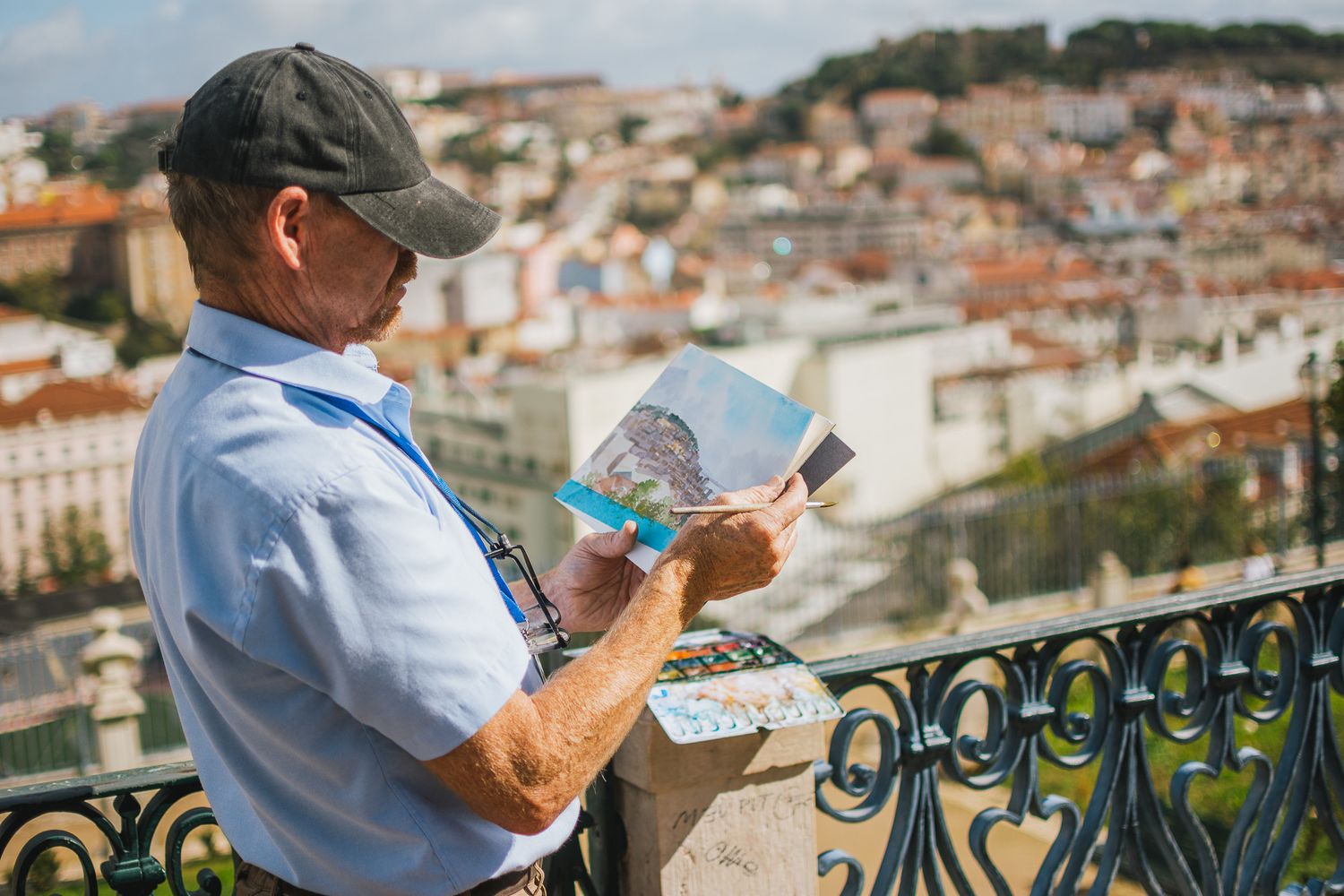 Tourist consulting a map while standing at scenic viewpoint overlooking city rooftops.