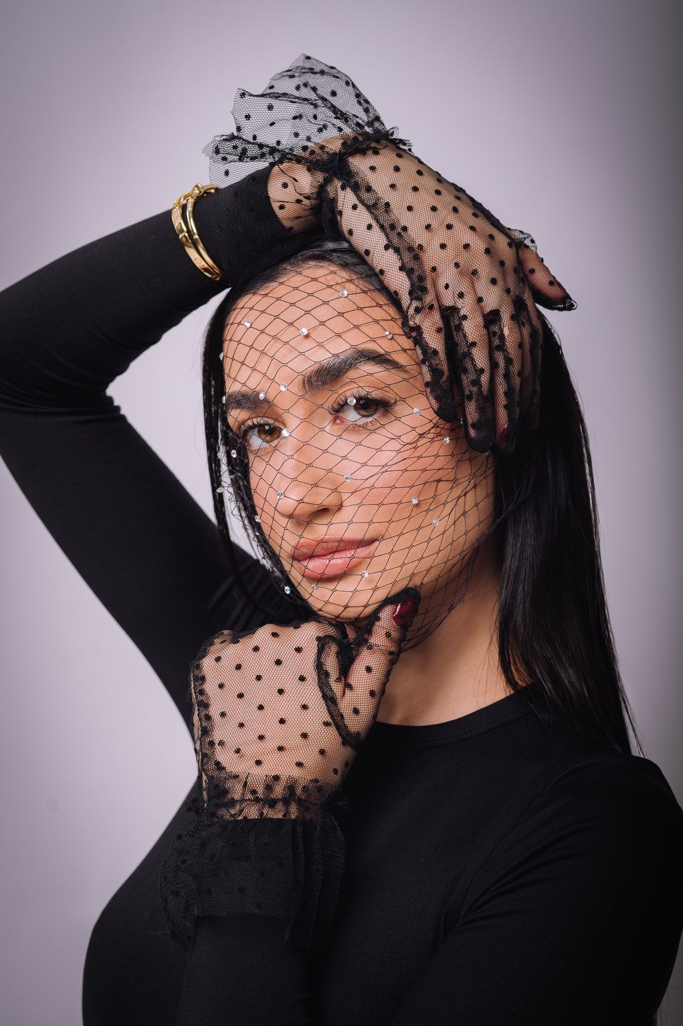 Fashion portrait with polka dot veil and black lace gloves.