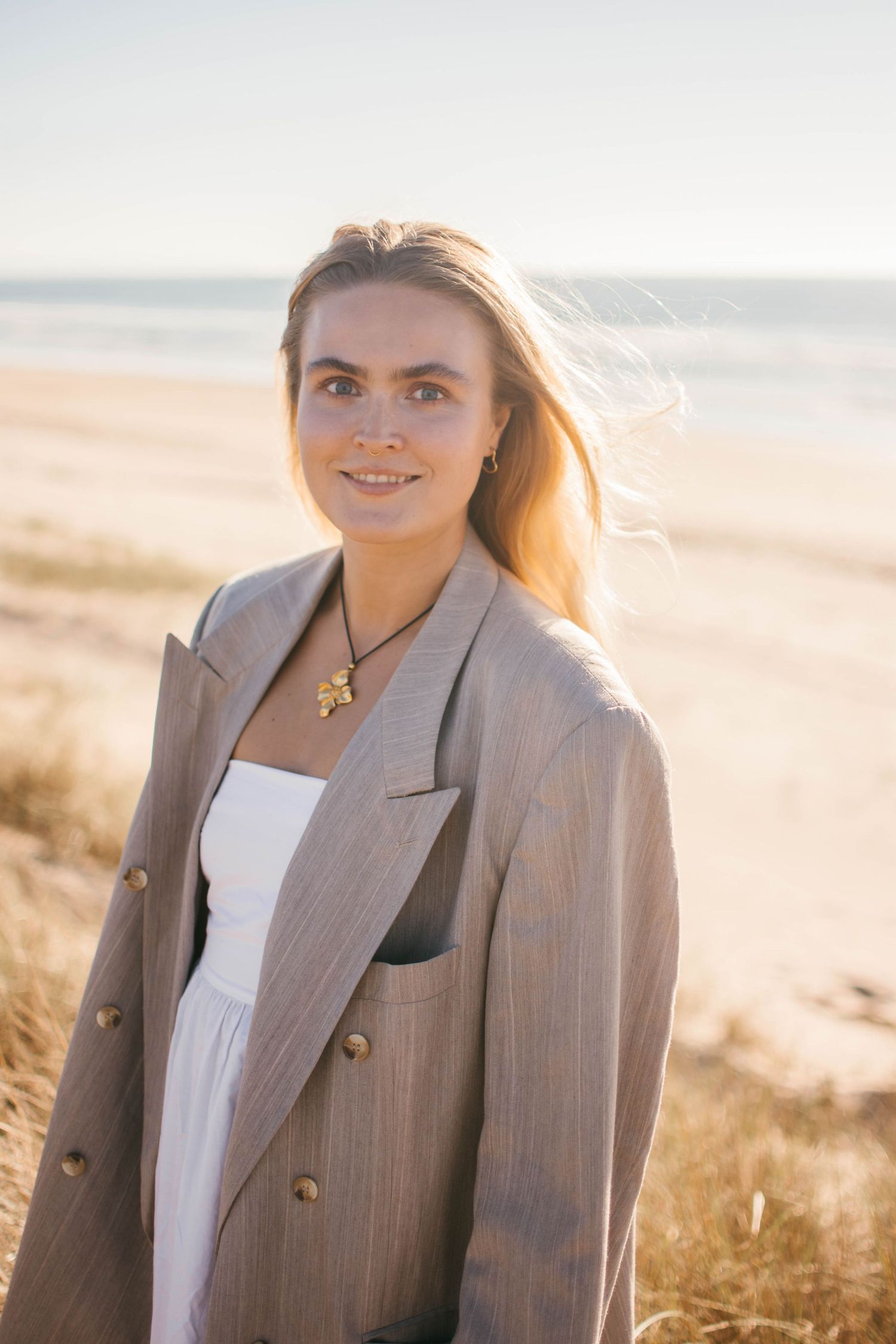 Portrait session at the beach featuring someone in a gray blazer during golden hour.