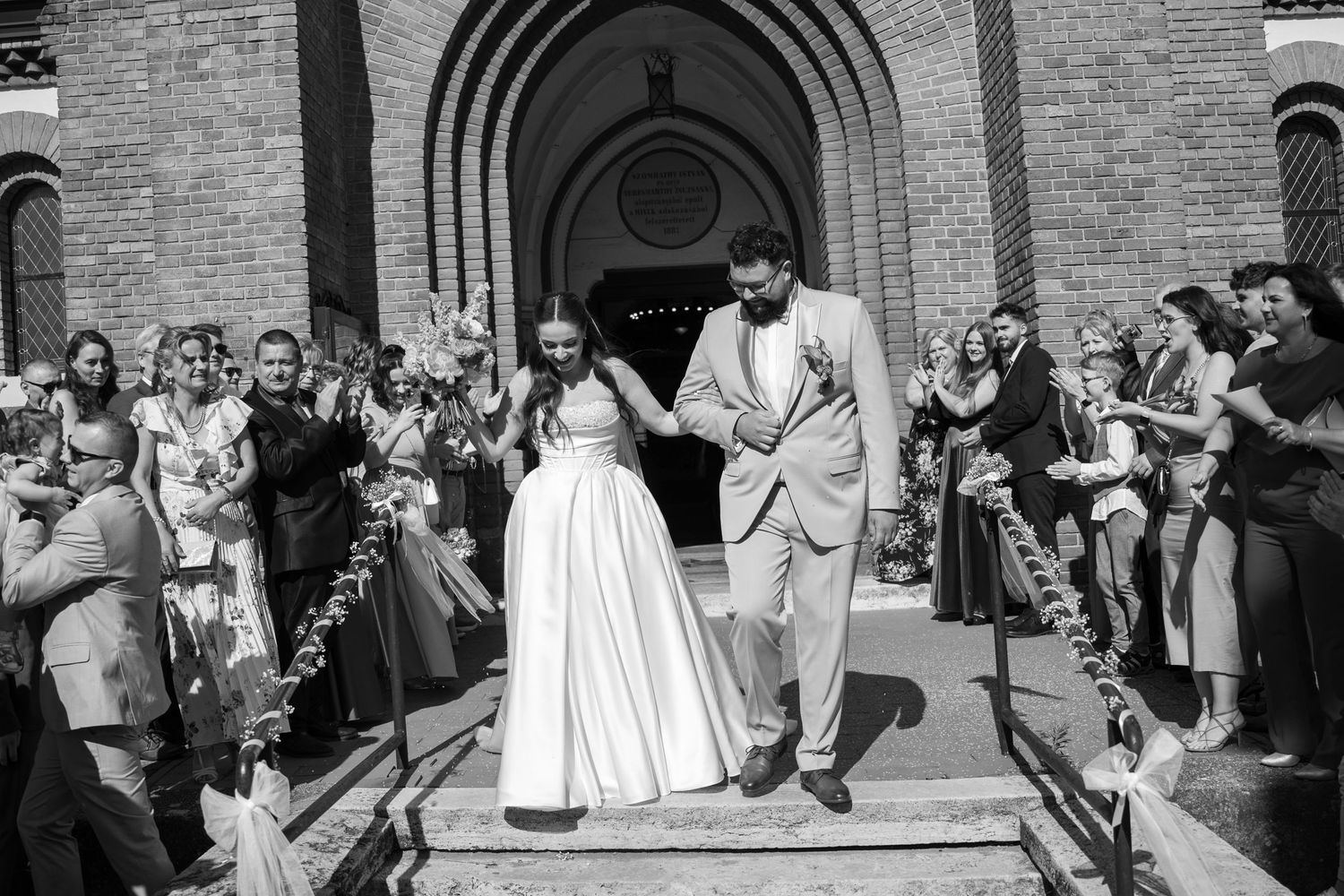 Wedding guests throw rice at newlyweds exiting church after ceremony while celebrating joyfully on the steps.