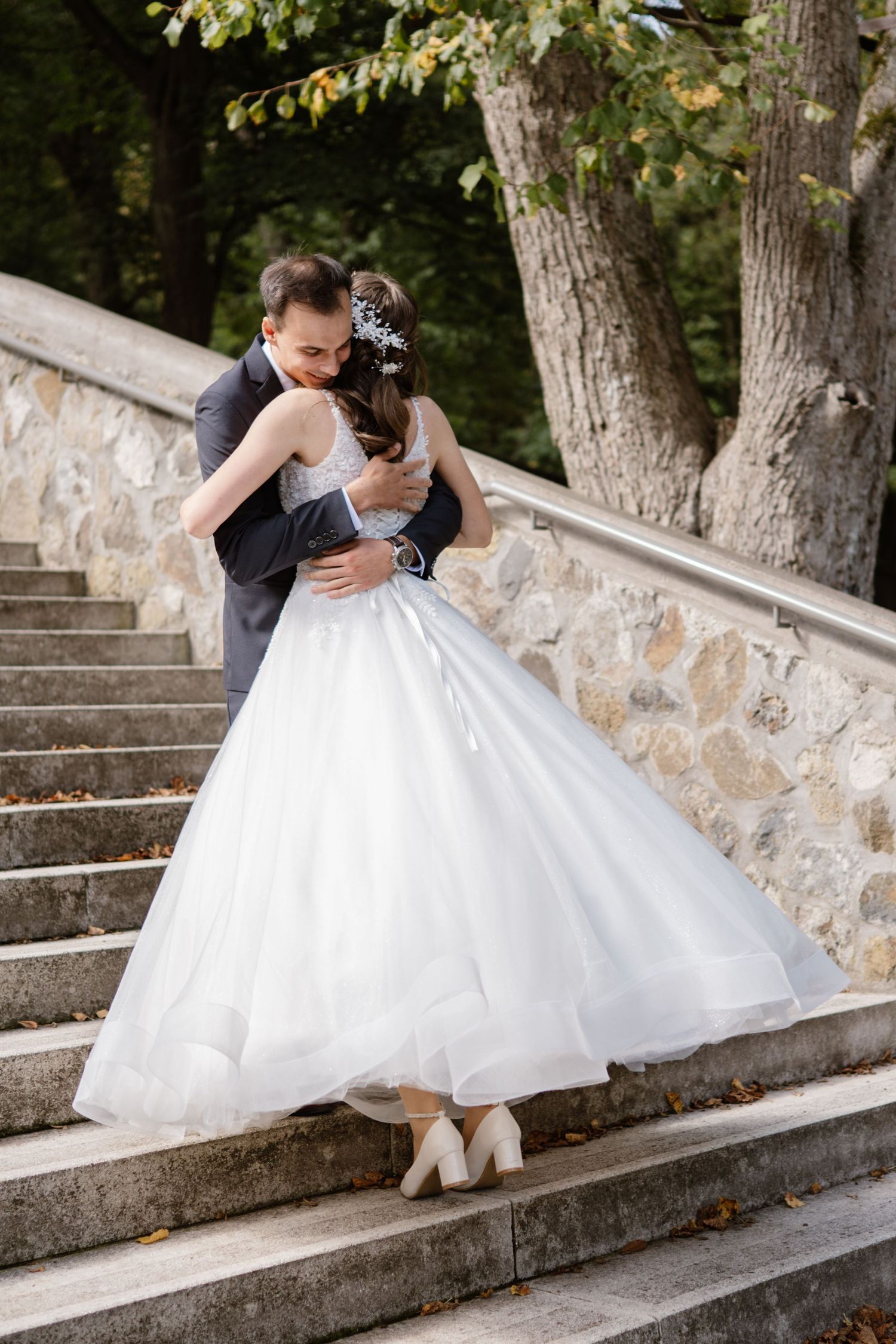 Couple poses romantically on stone steps during their wedding photoshoot.