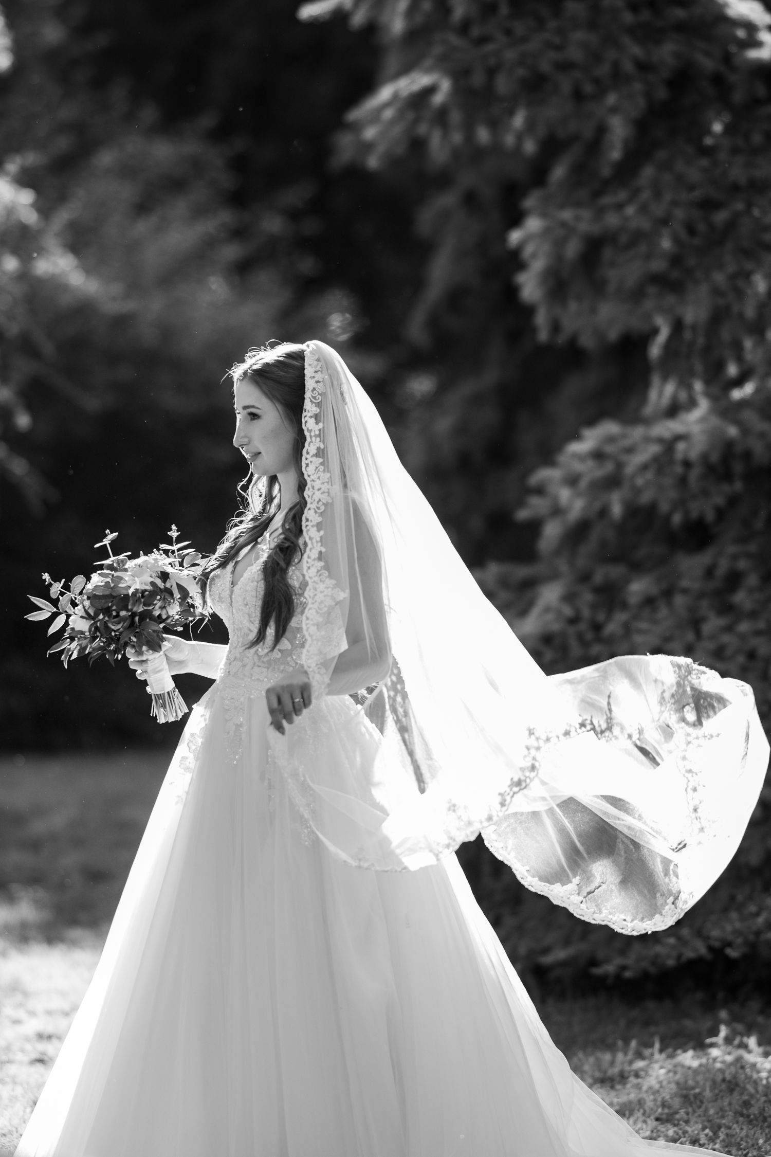 Flowing white wedding dress with delicate lace details captured in black and white.