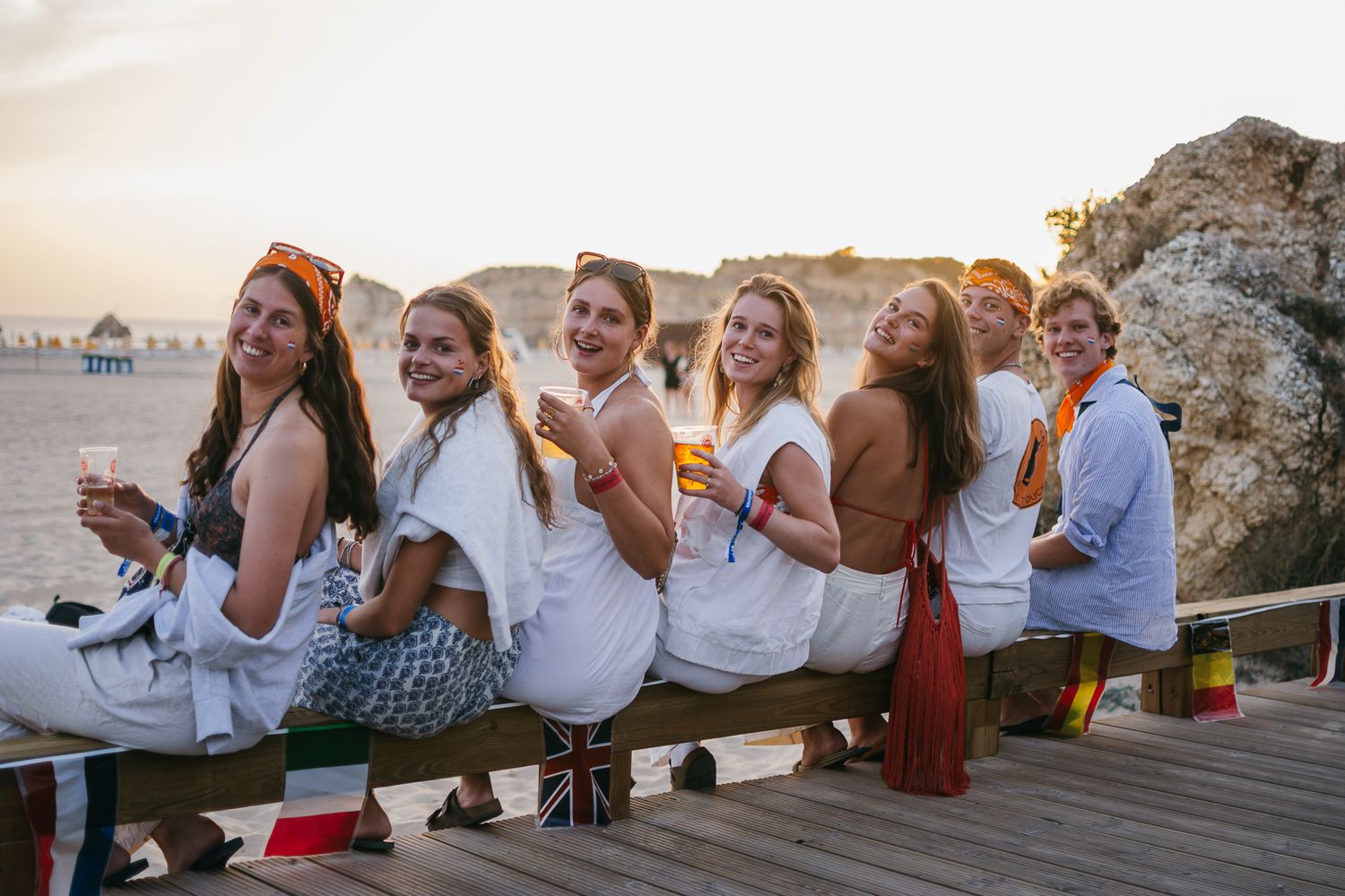 Friends posing together on a seaside wall during sunset.