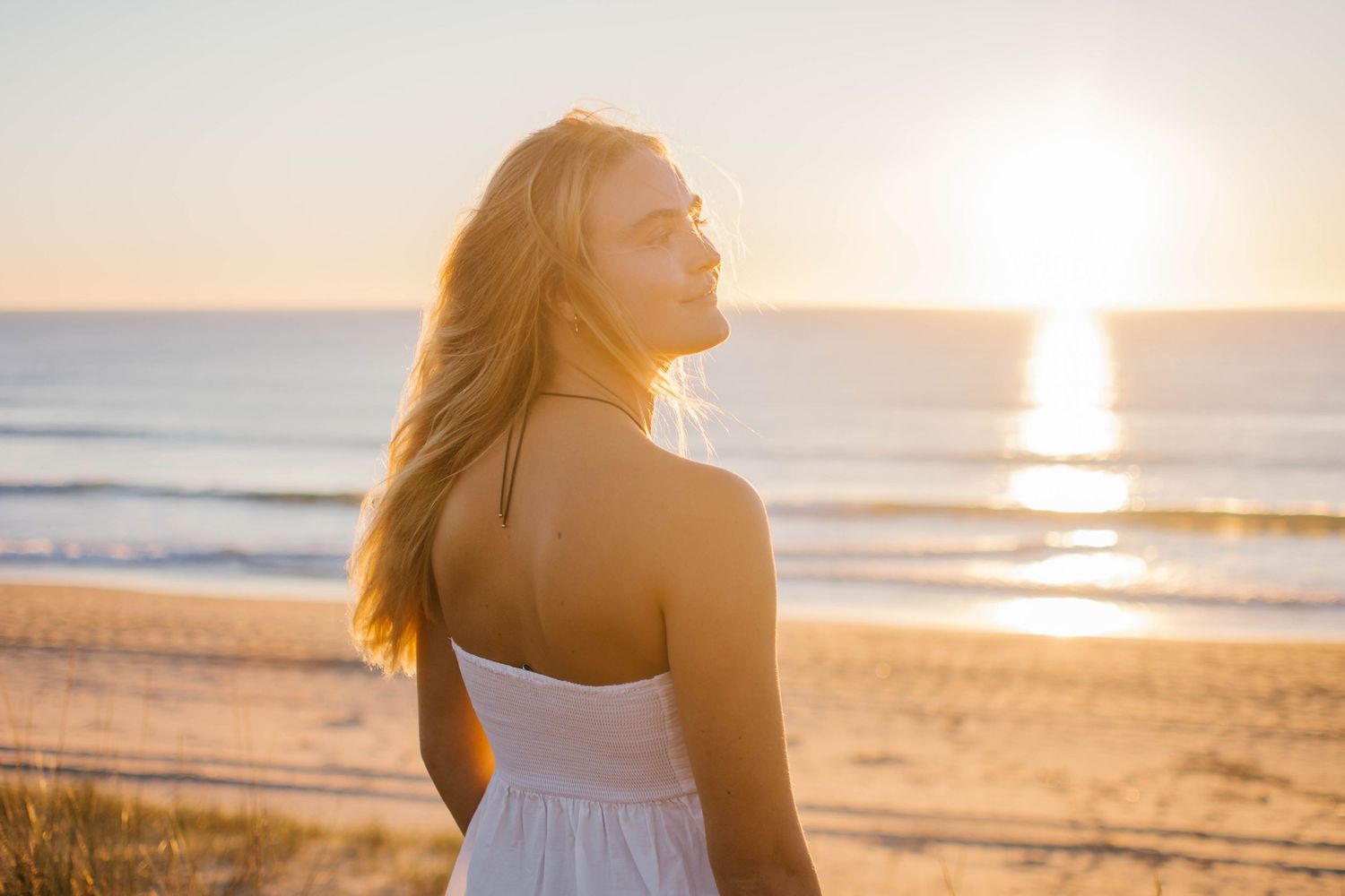 Silhouette of a person enjoying sunset at the beach with hair flowing in the wind.