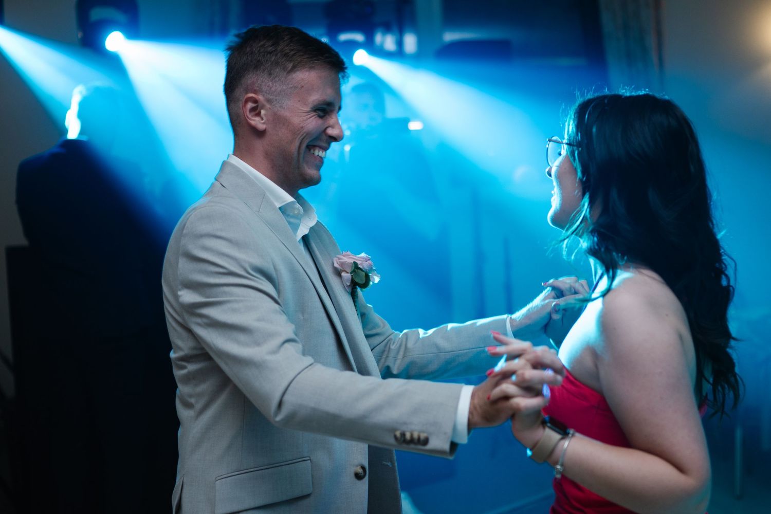 Couples dance together under dramatic blue lighting at an evening wedding reception.