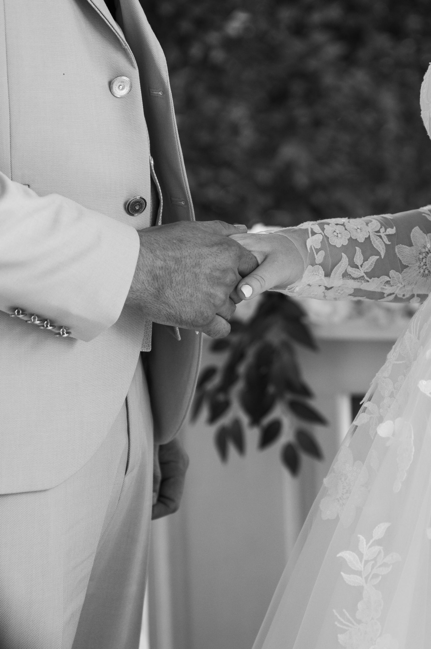 Close-up detail of a bride and groom's hands during their wedding ceremony.