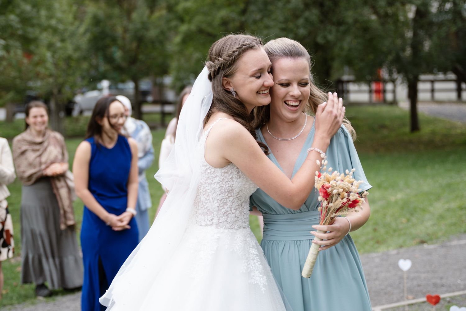 Wedding party in blue bridesmaid dresses and formal attire poses together outdoors.