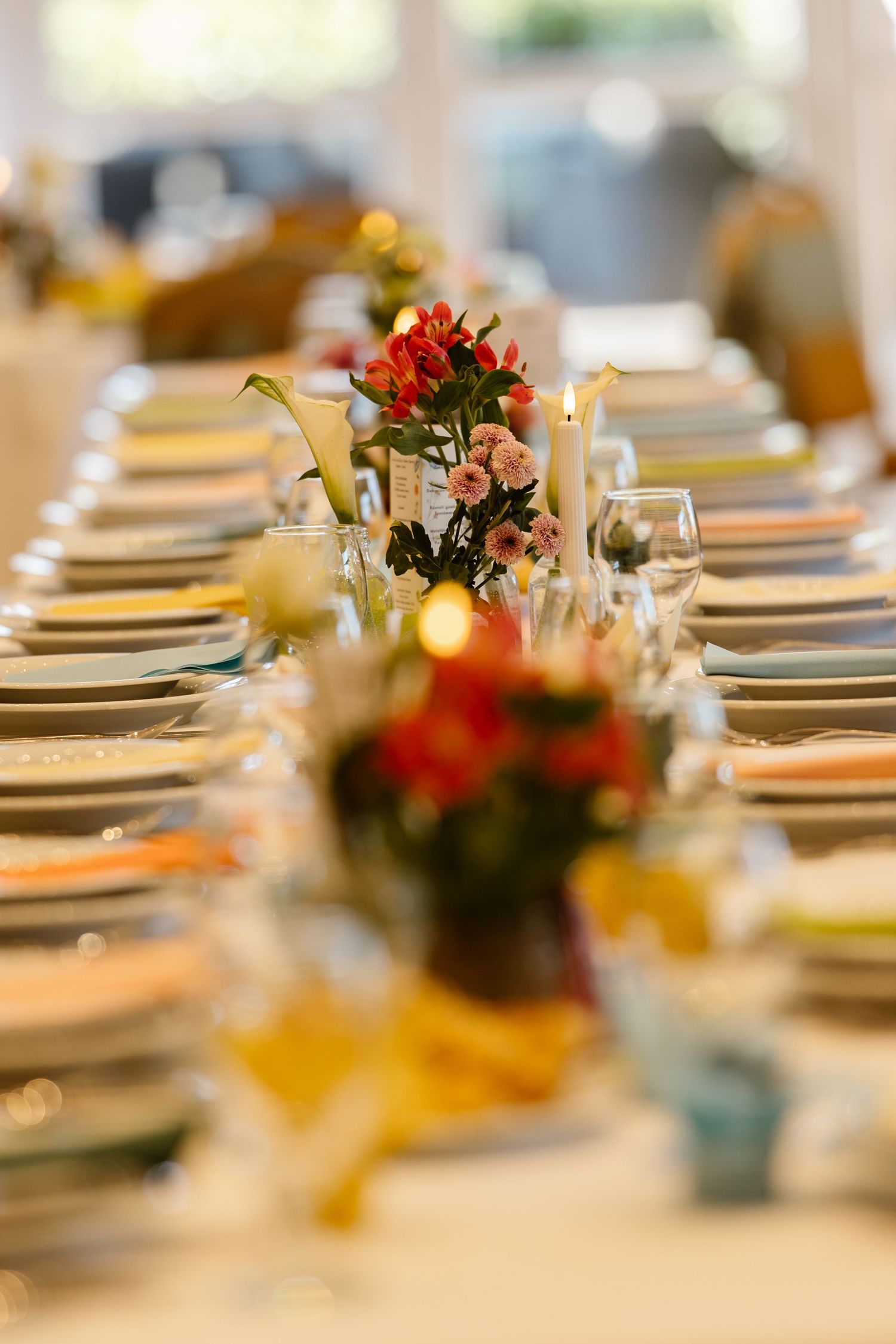 Elegant wedding reception table setting with floral centerpieces and place settings.