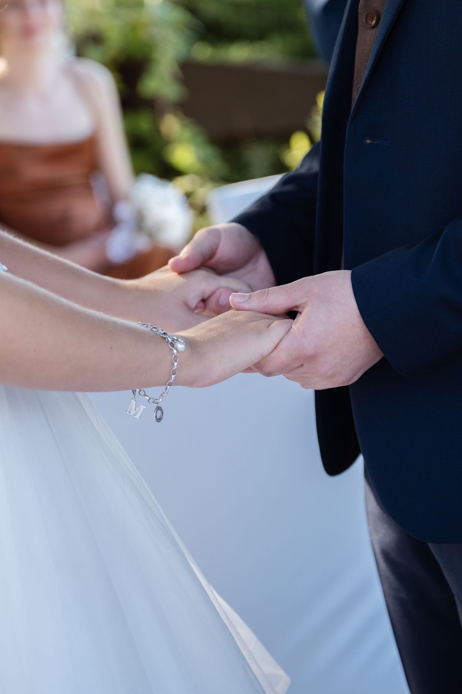 Close-up shots of hands exchanging wedding rings during an outdoor ceremony.