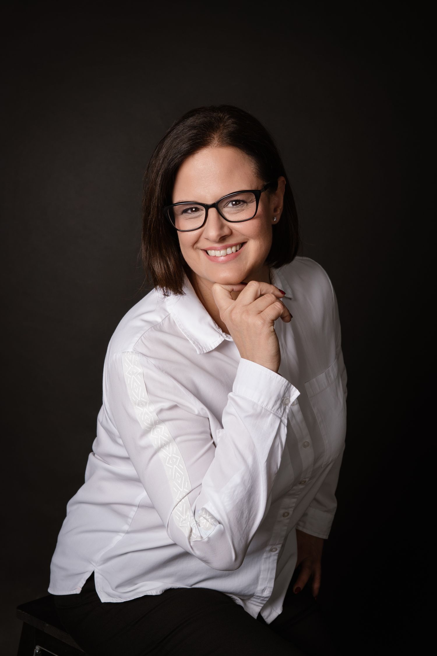 Studio portraits featuring white button-down shirt and glasses against dark background.