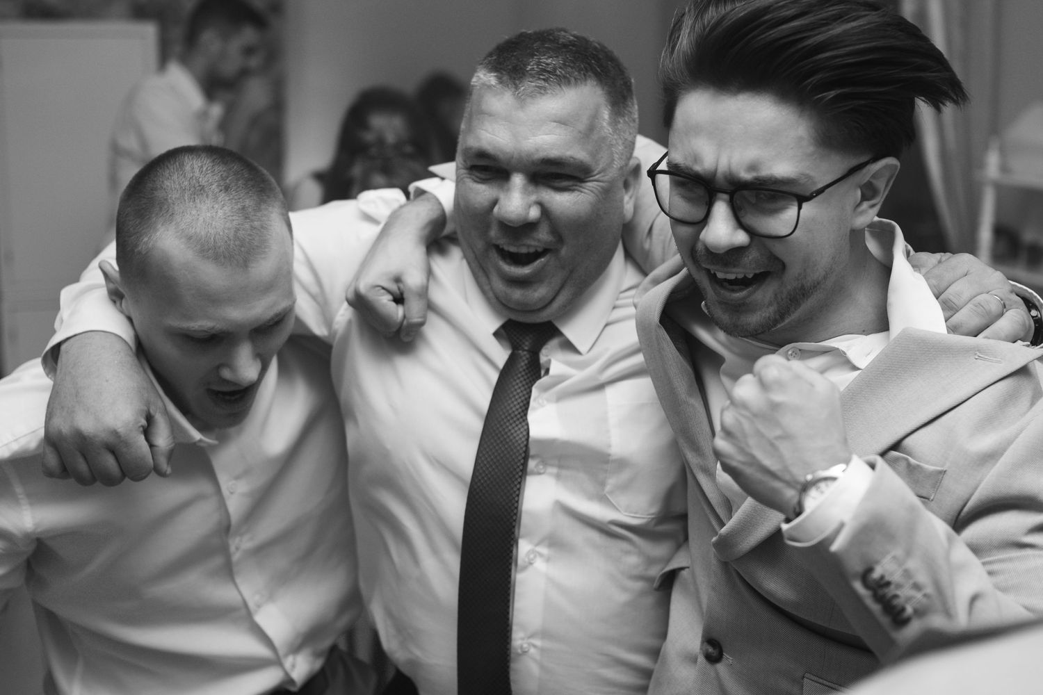 Group of people in formal attire laughing and celebrating at an indoor event.
