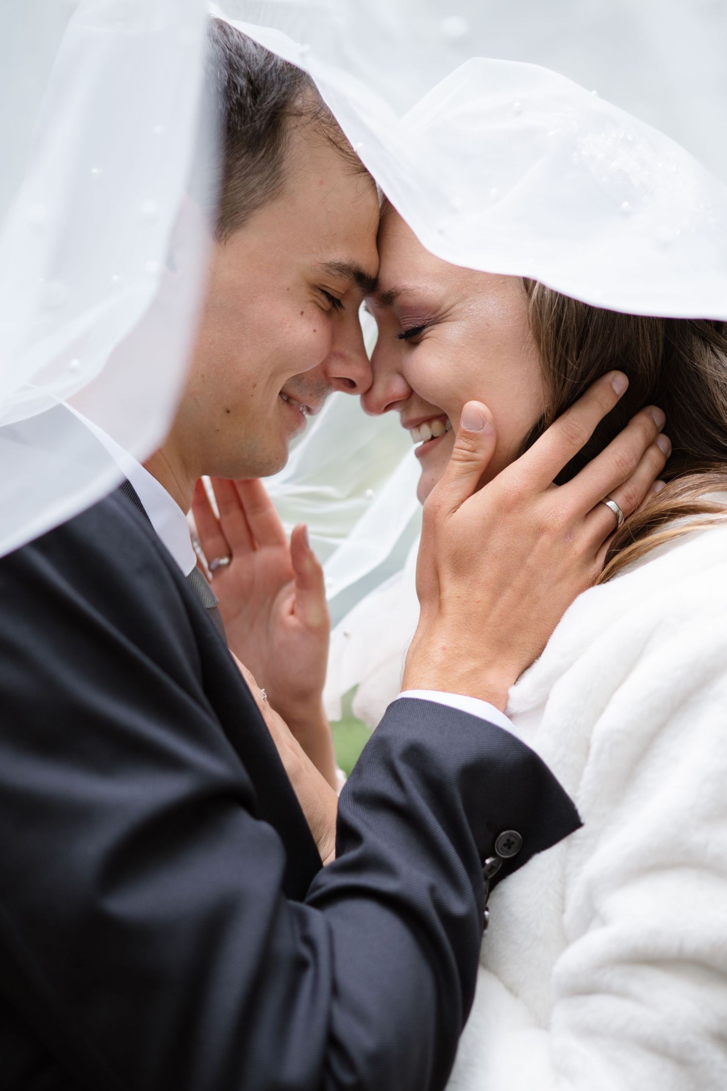A tender moment shared between a couple under a flowing white veil.