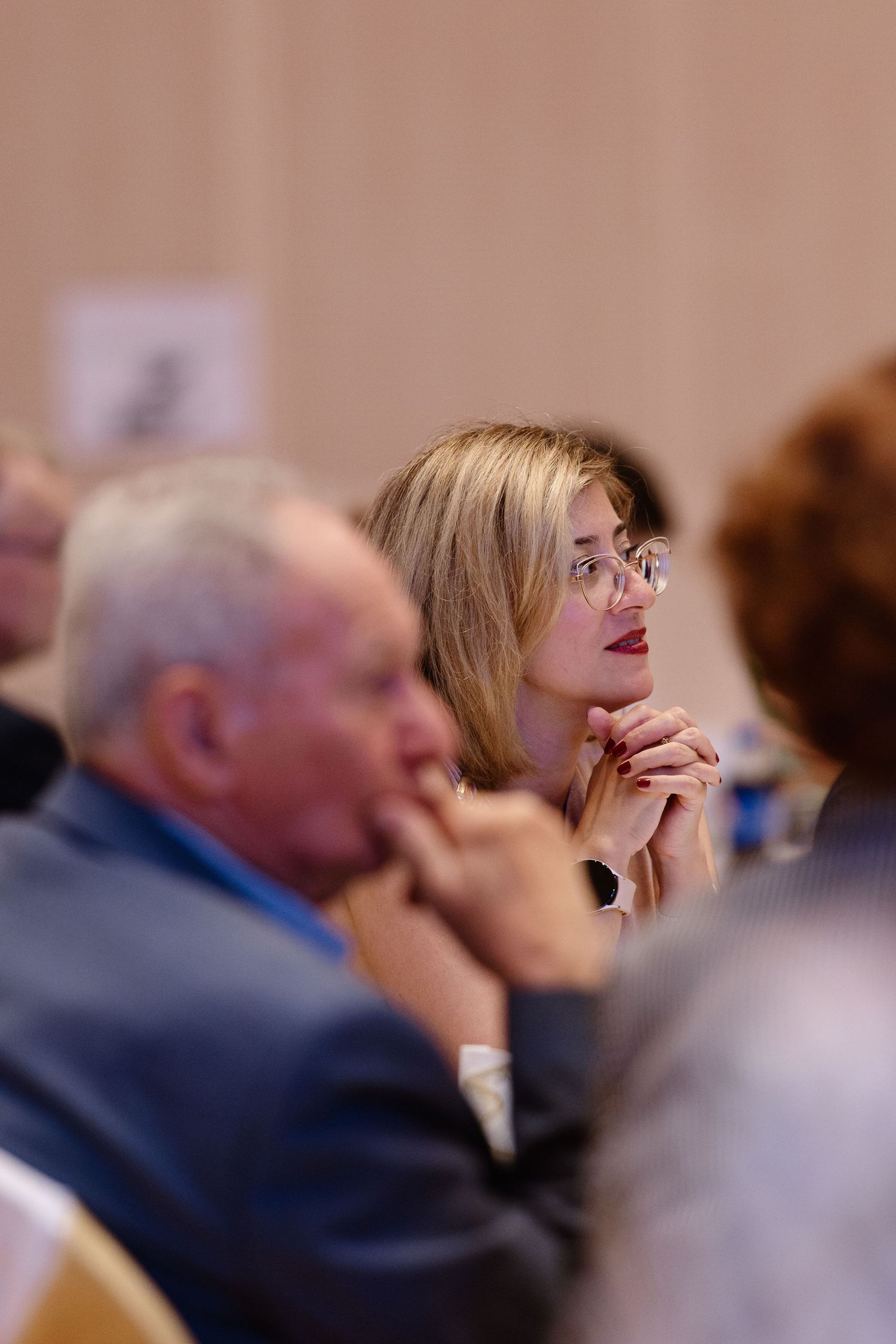 People in an audience react with laughter and smiles during what appears to be a presentation or event.