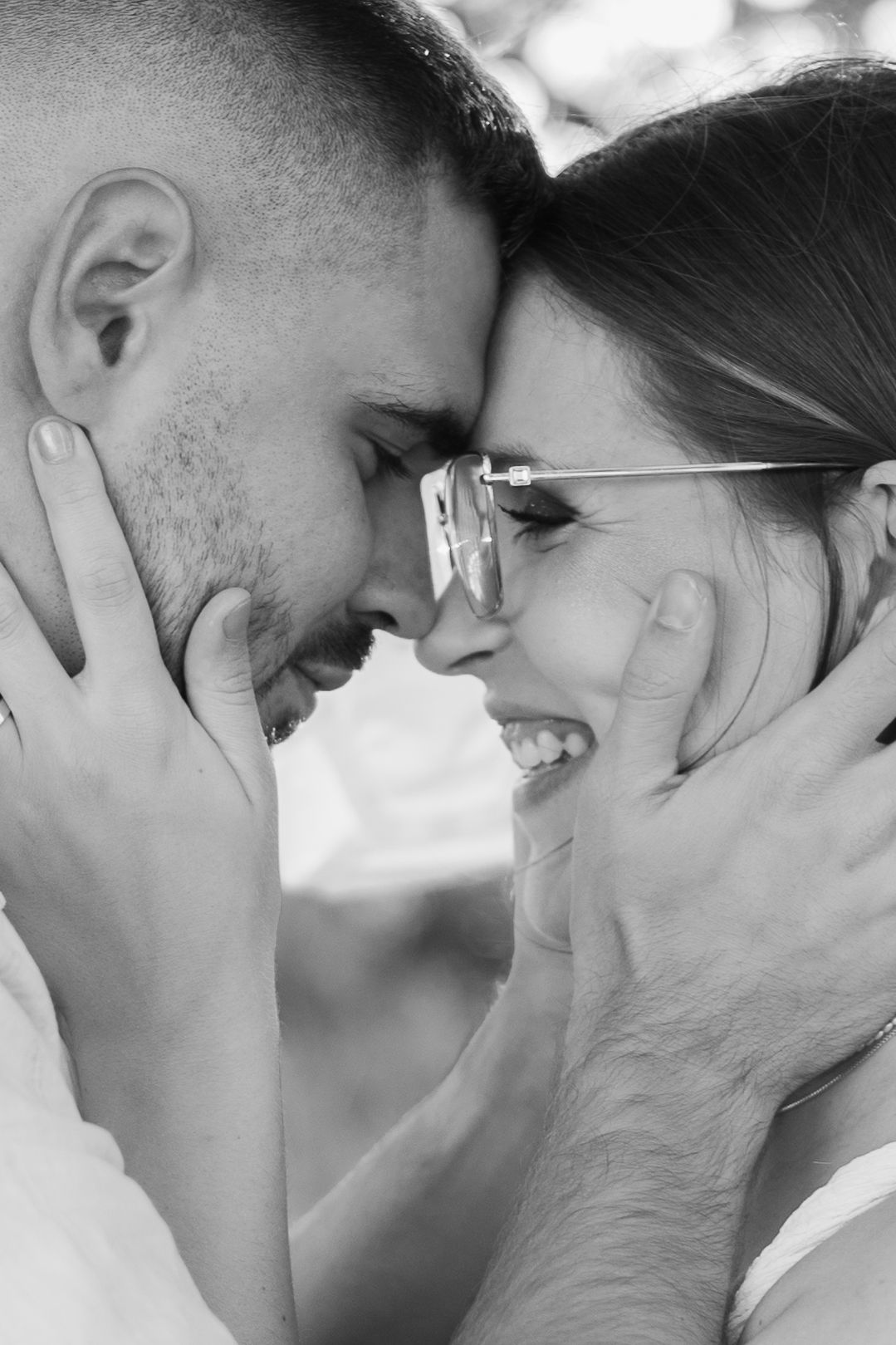 A tender black and white close-up portrait of a romantic couple sharing an intimate moment with their faces touching.