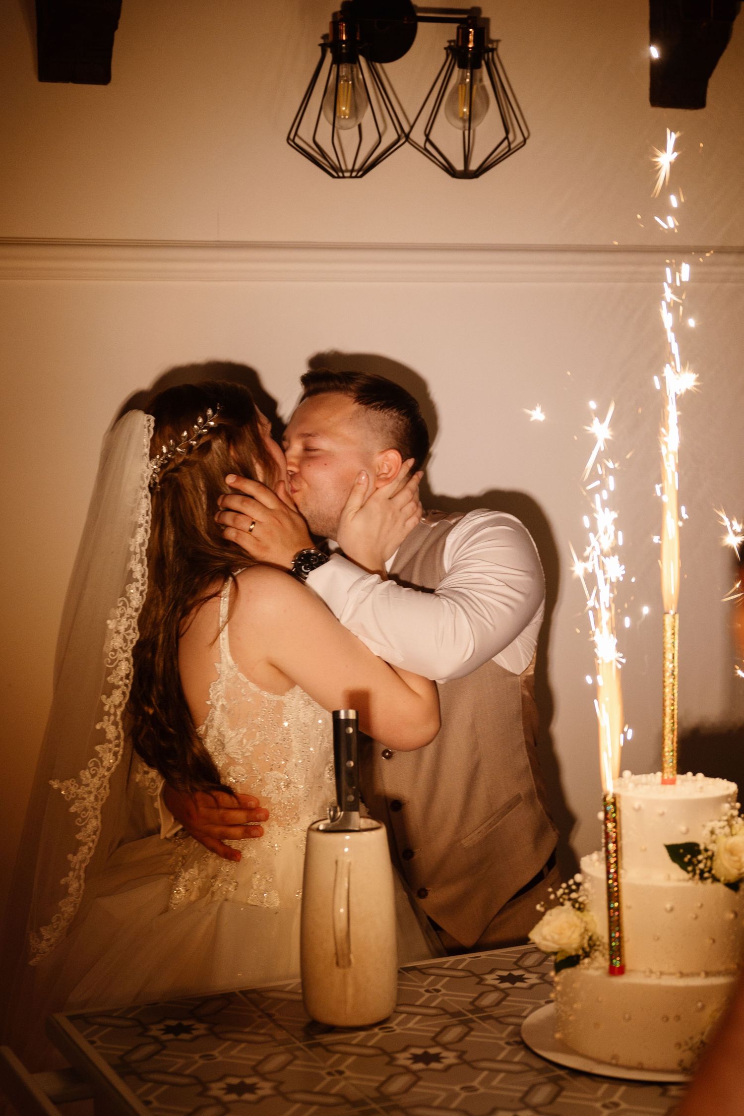 Wedding couple sharing an intimate moment in front of sparklers and a wedding cake.