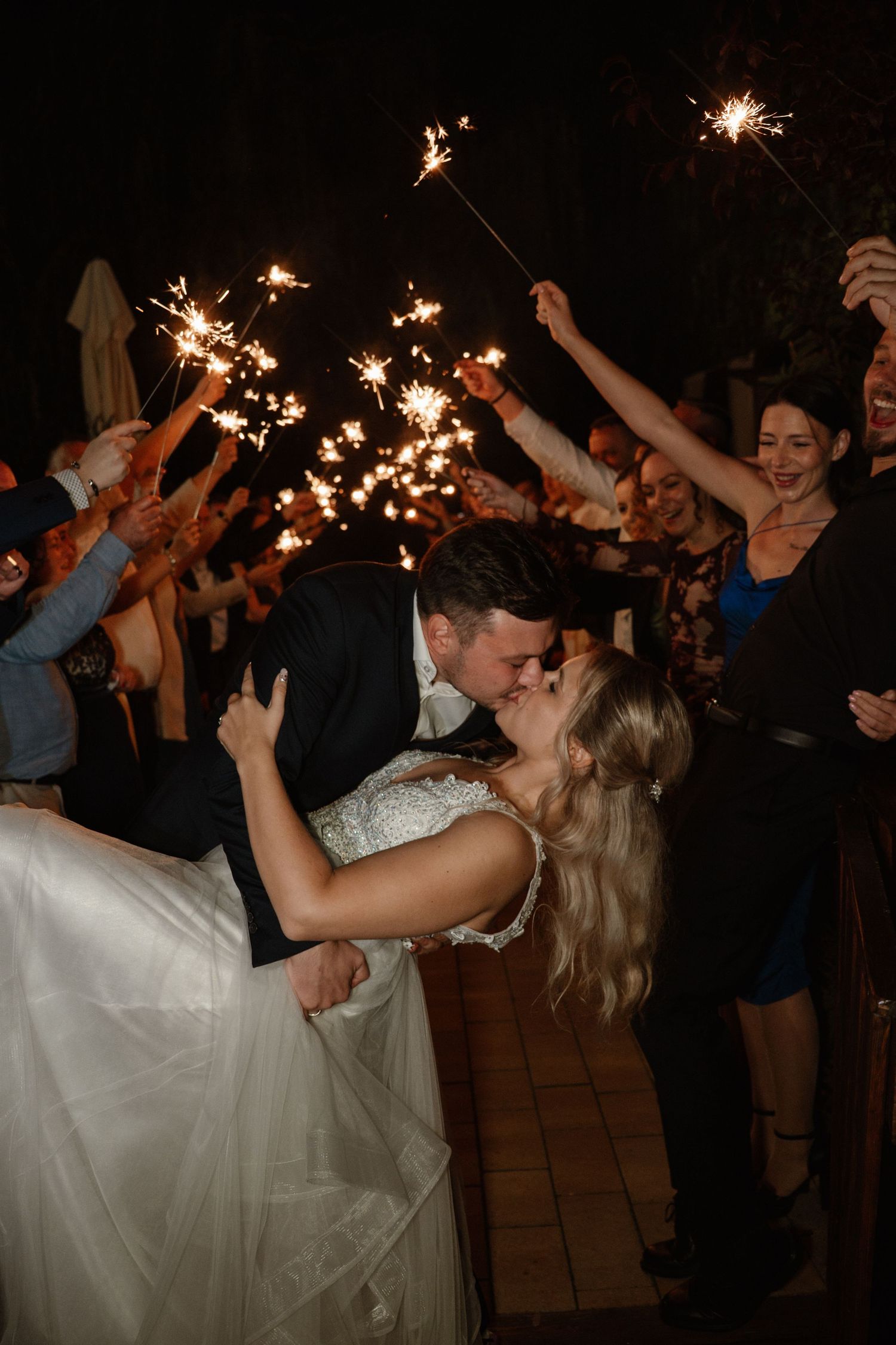 Couple shares romantic sparkler dance moment at outdoor evening wedding celebration.