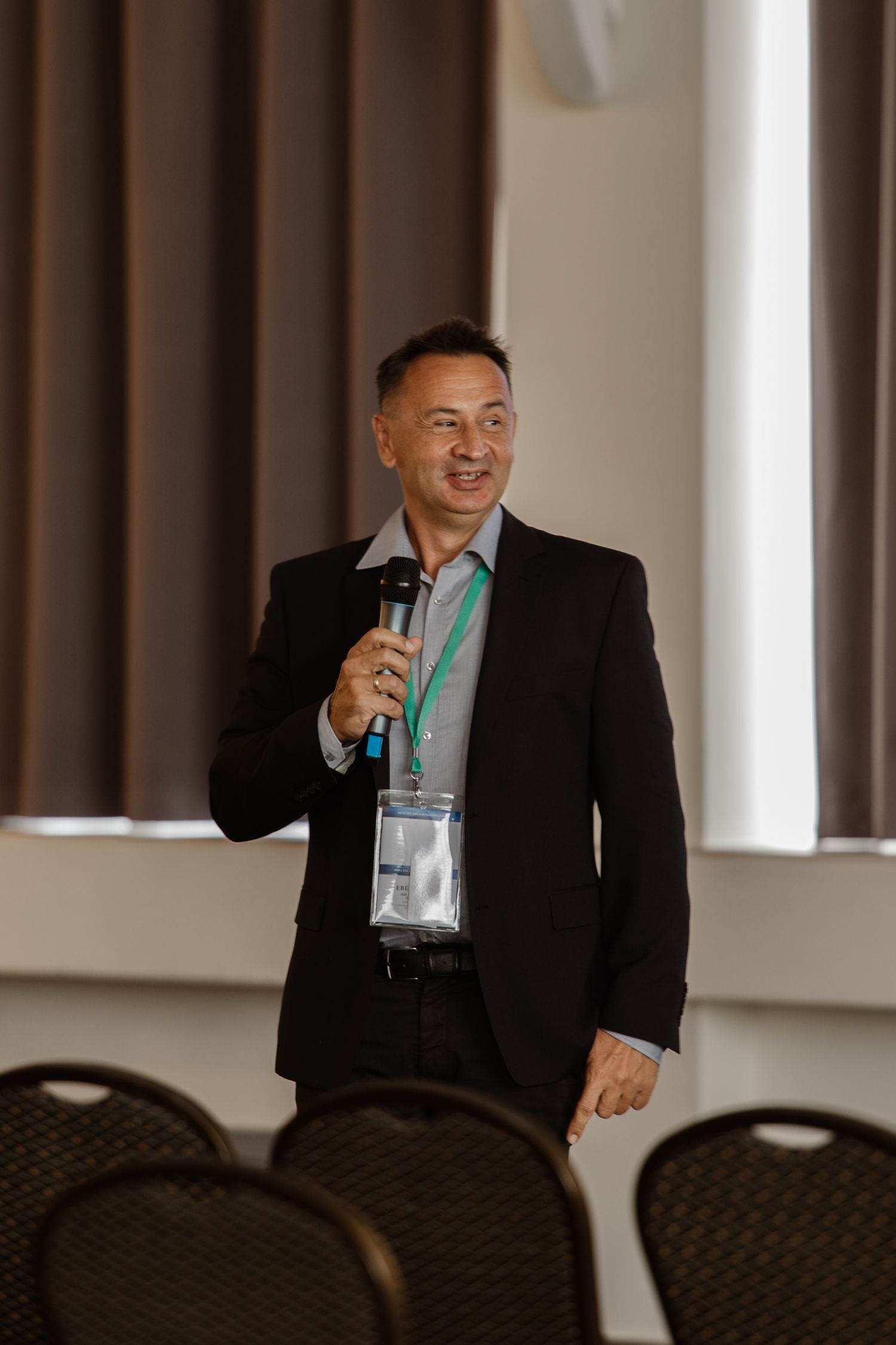Speaker presenting with microphone at conference in professional attire.
