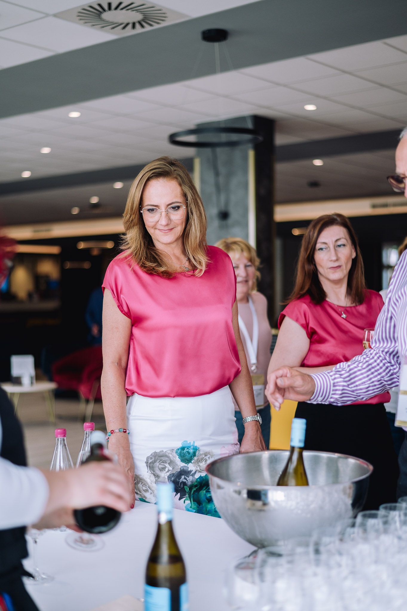Event attendees gathered around a table with champagne and ice buckets at a networking function.