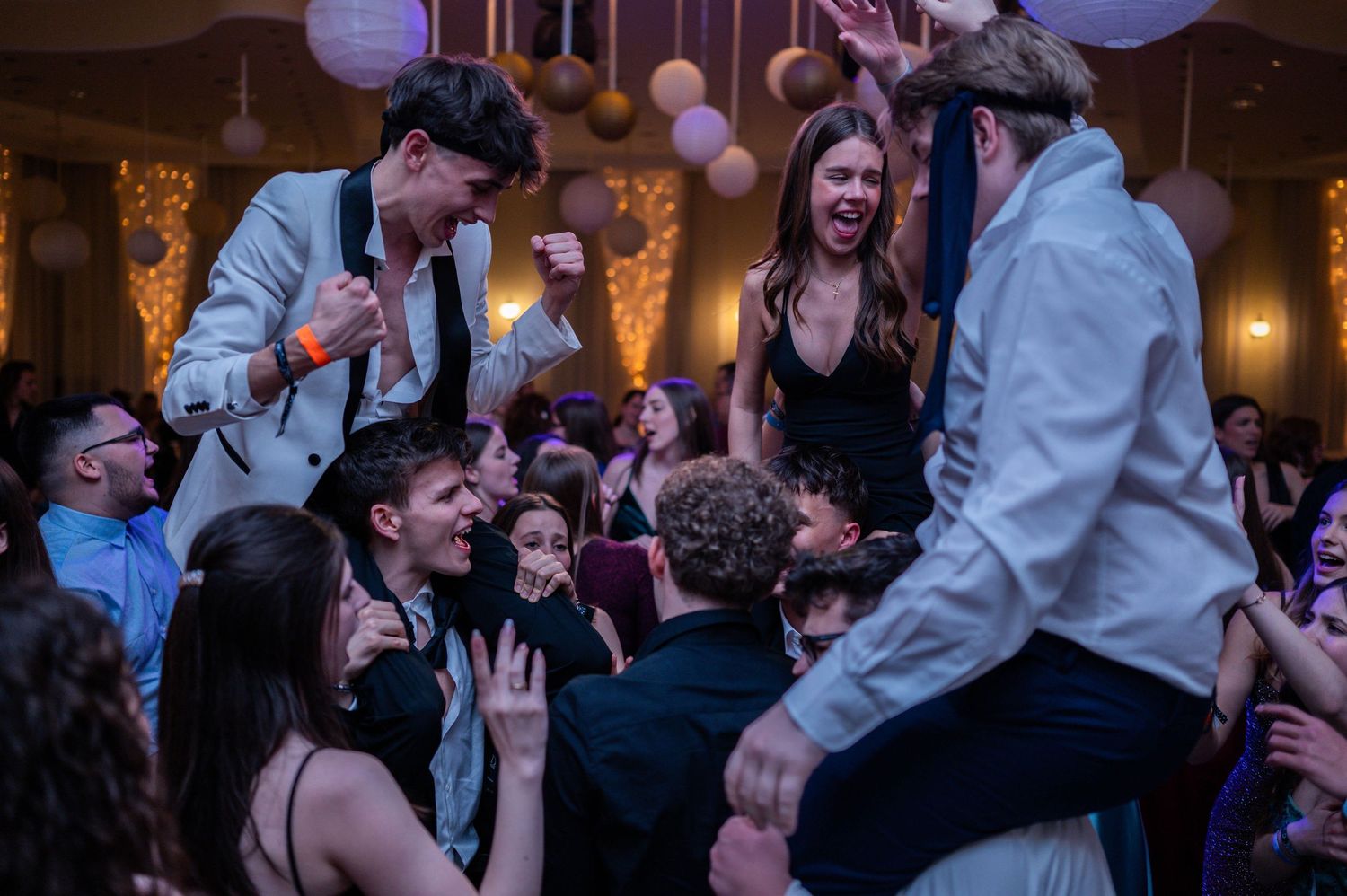 Wedding celebration showing guests dancing and mingling under paper lanterns and string lights.