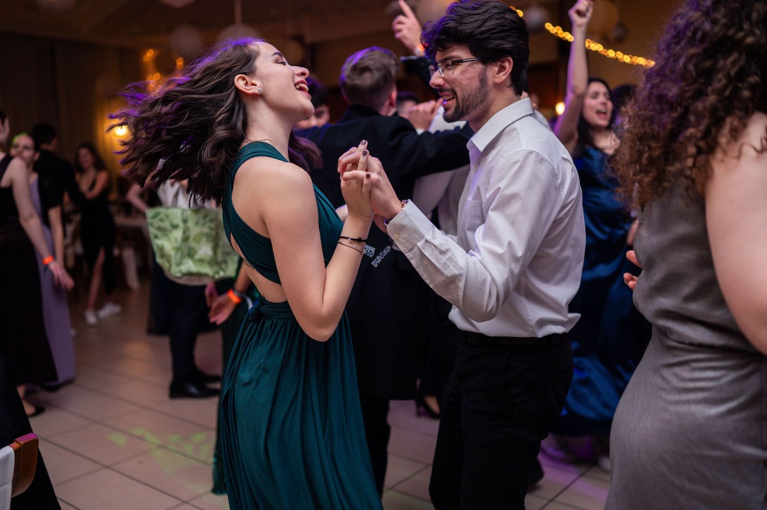 Guests dancing and celebrating at an elegant wedding reception with mood lighting.