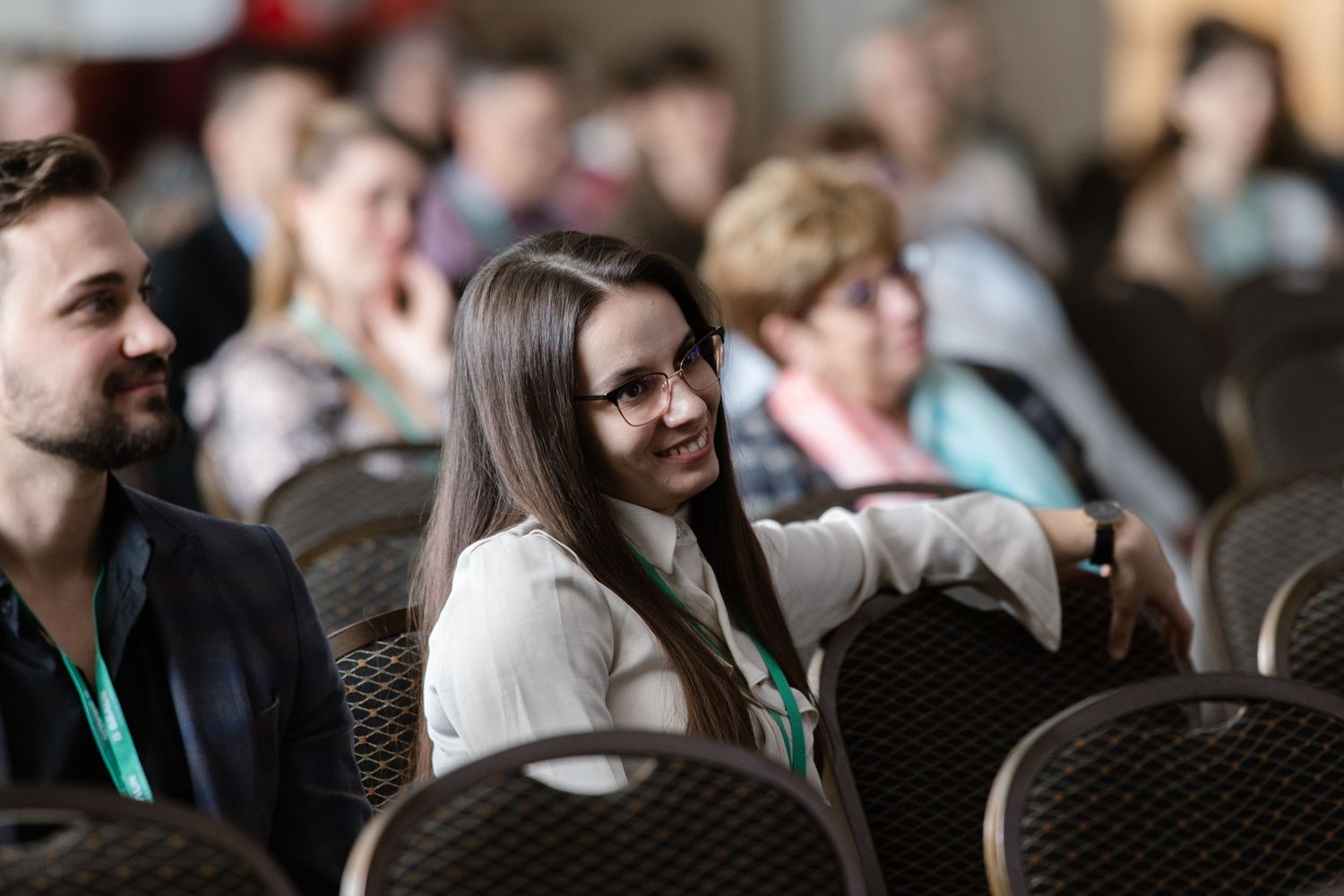 Conference attendees sitting in audience chairs during presentation.
