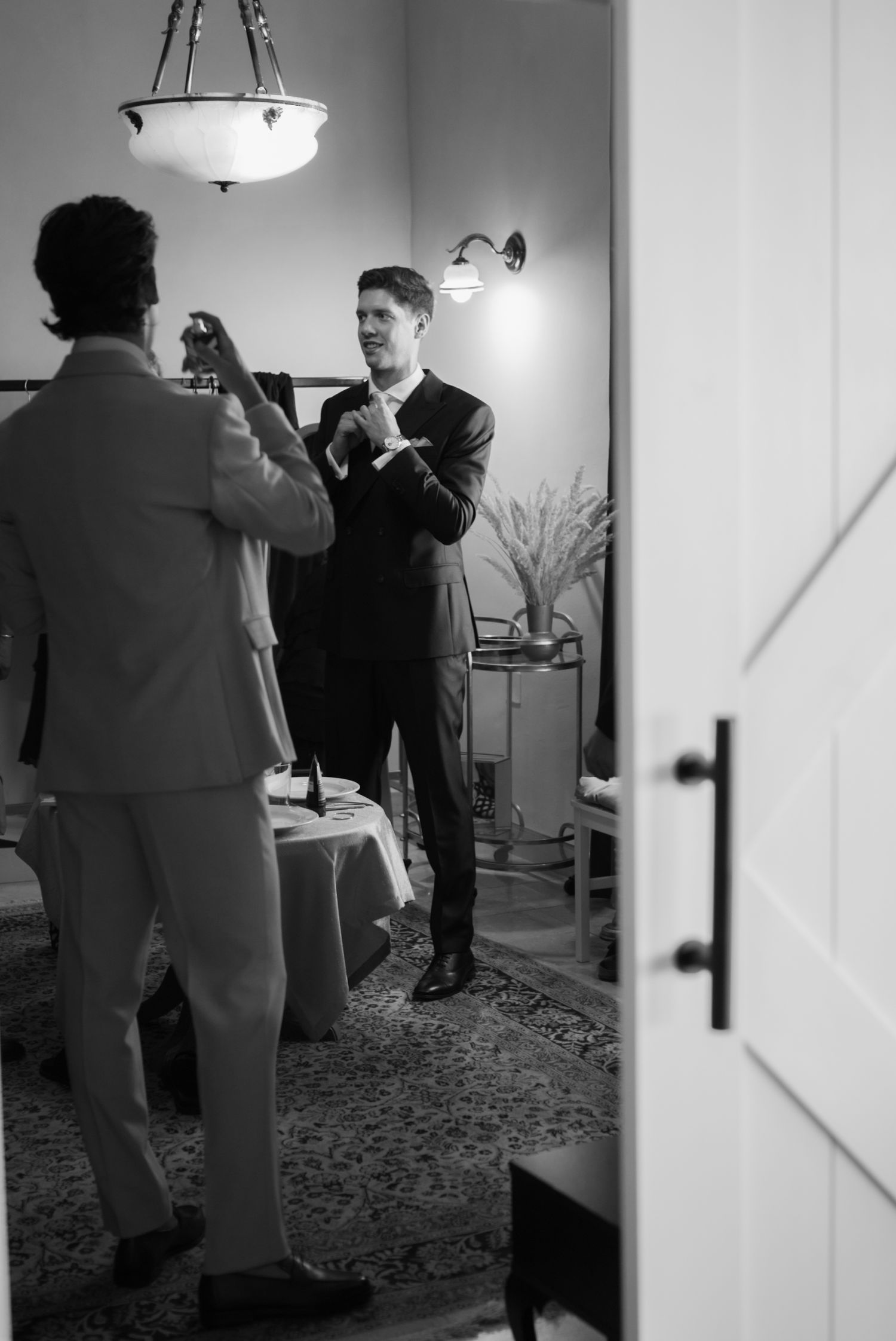 Black and white photo of two grooms getting ready, adjusting cufflinks before their wedding ceremony.