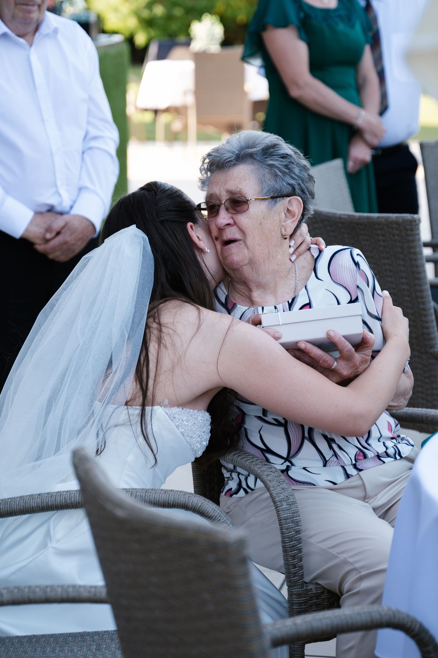 A series of photos showing a tender moment between two people embracing while seated on outdoor patio furniture.