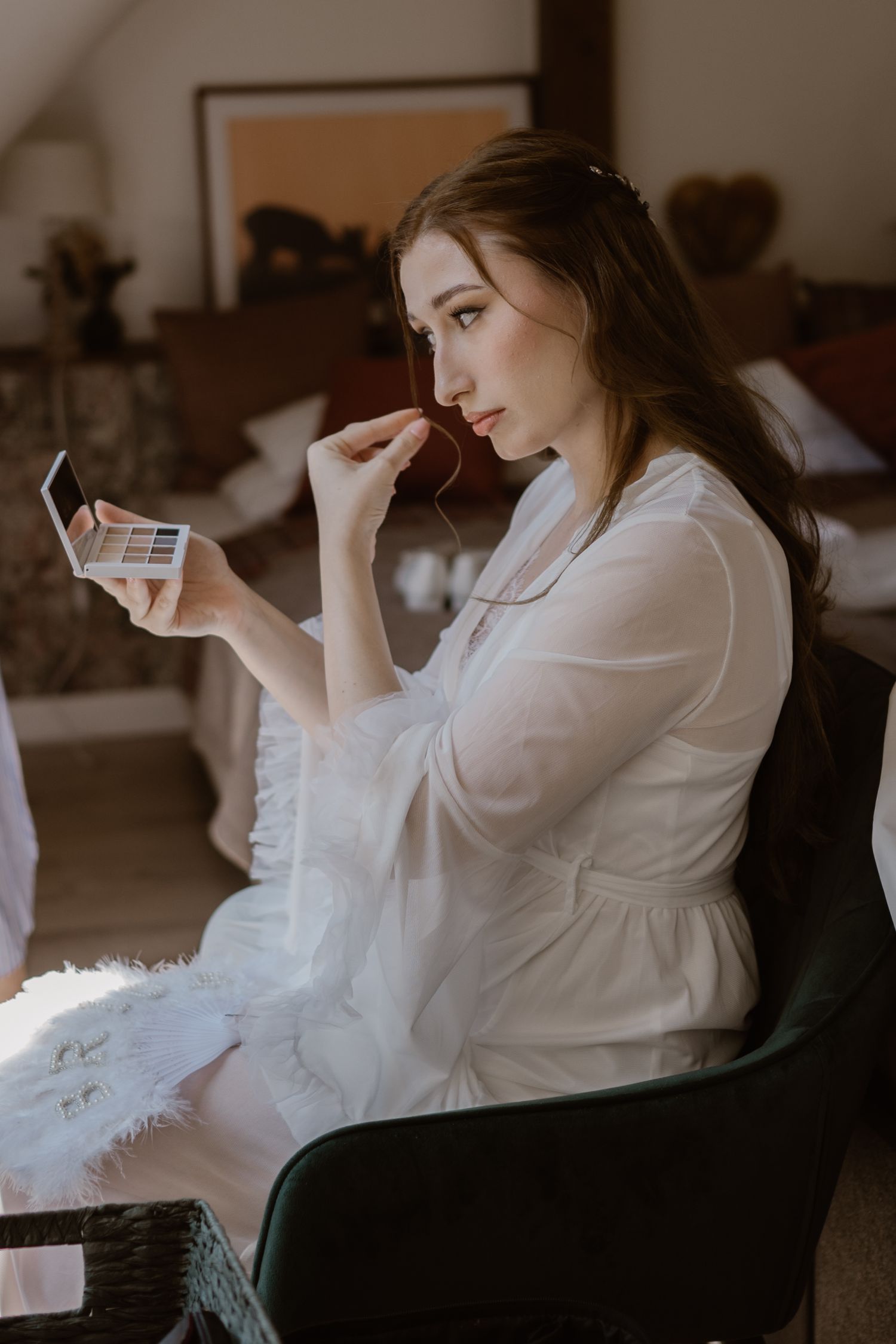 Person in white robe sitting in dim lighting looking at phone.