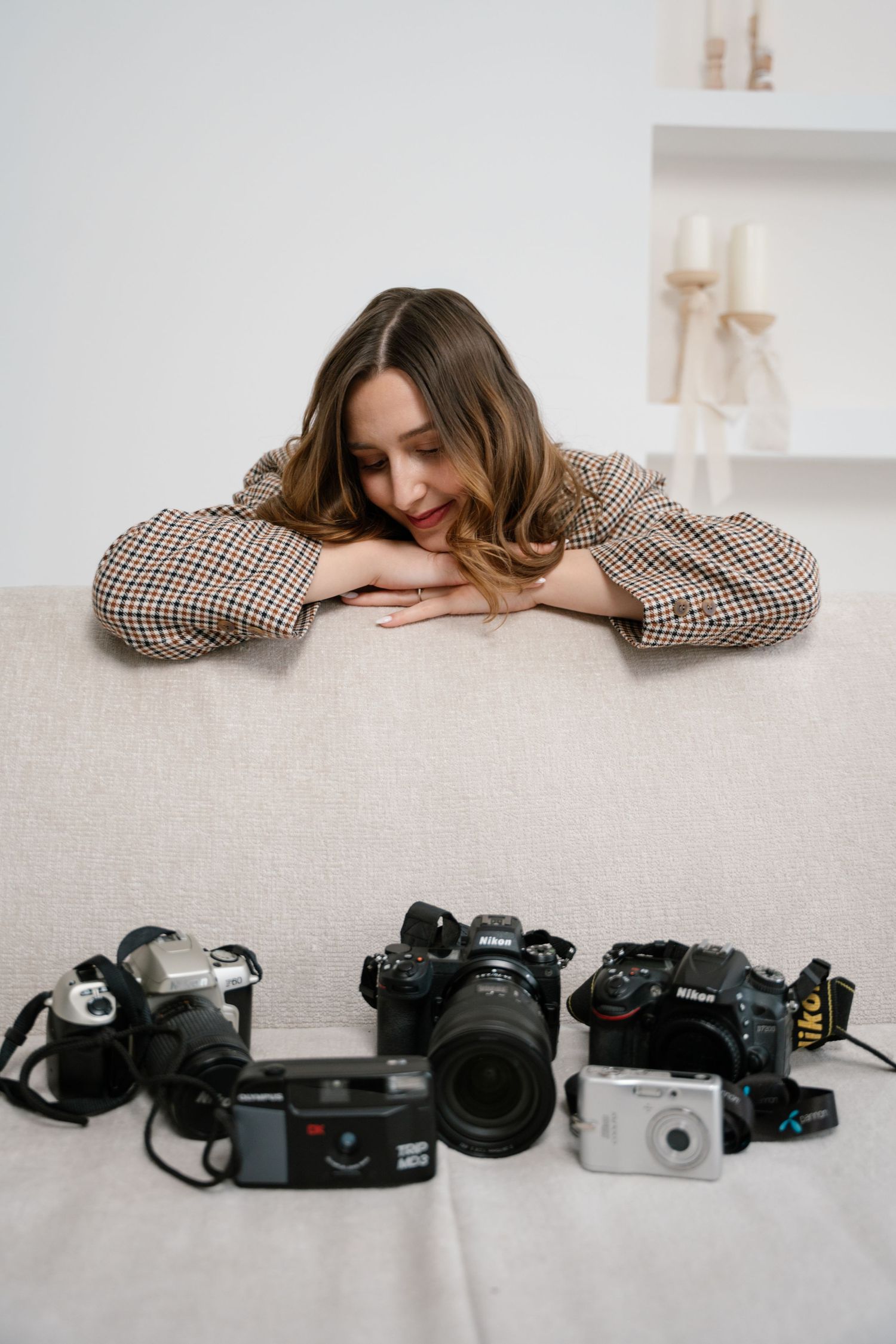 A photographer rests on a white surface while looking at a collection of vintage and modern cameras displayed below.