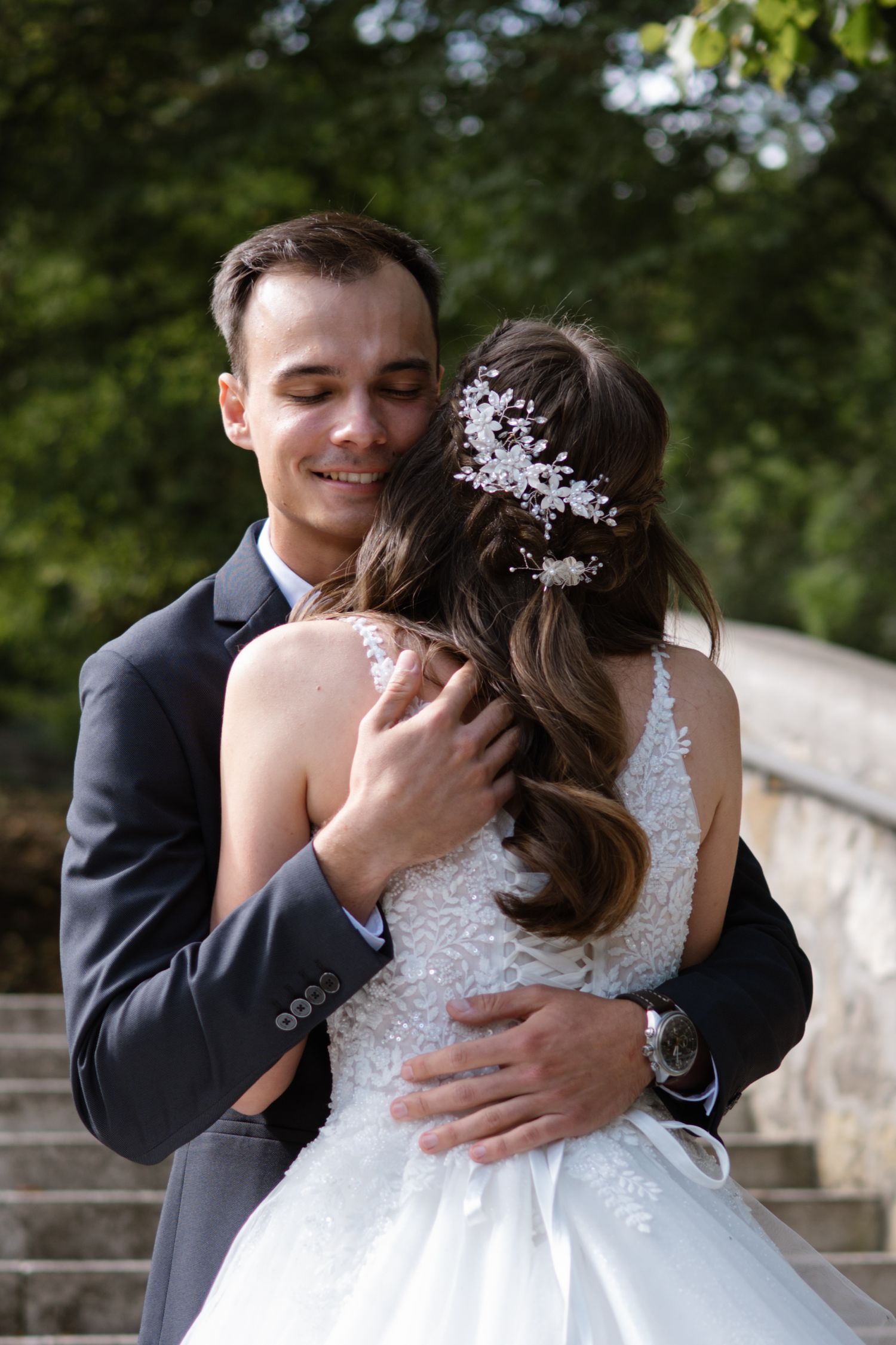 A romantic wedding portrait of a couple embracing on stone steps outdoors.