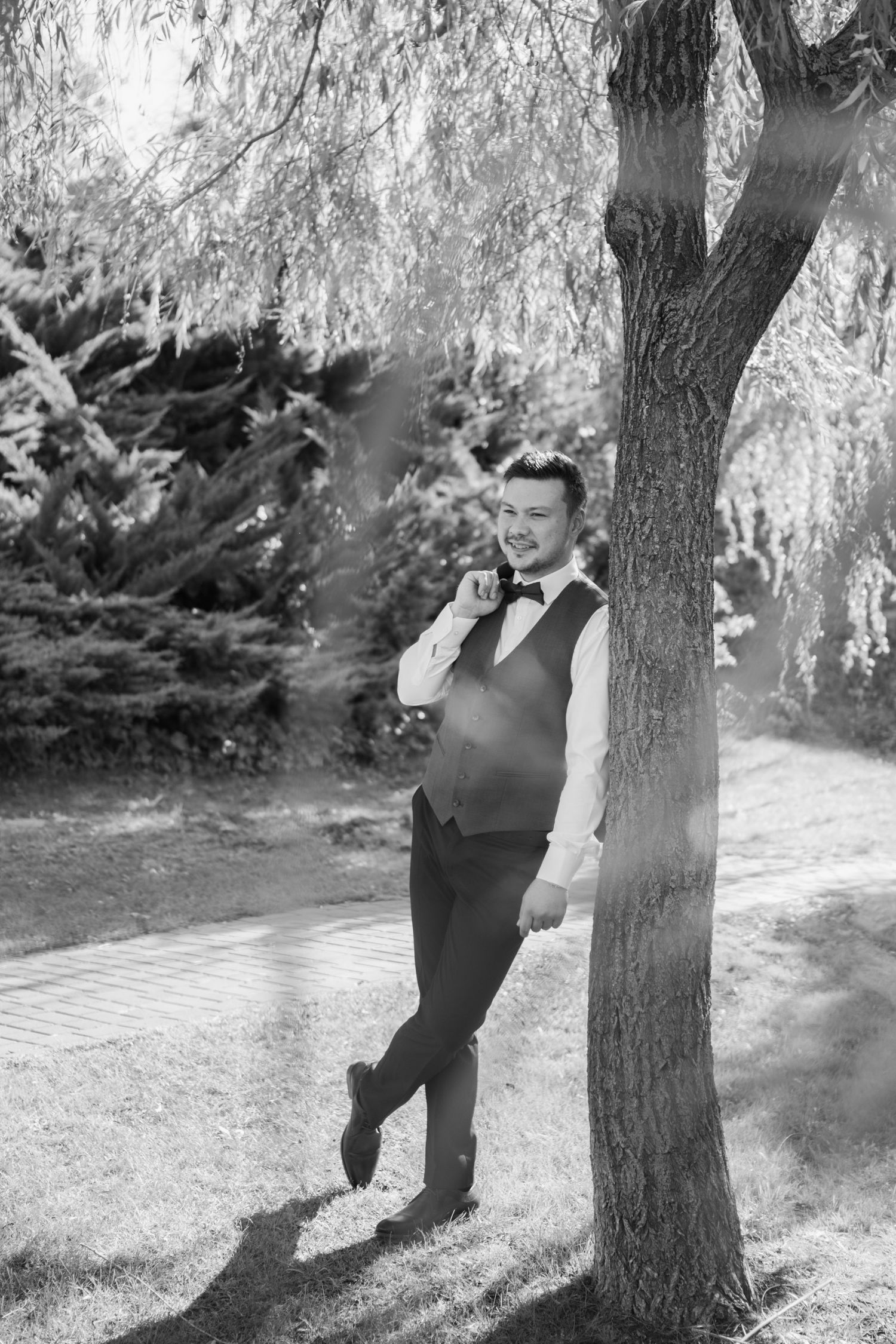Black and white photos of playful moments between the wedding couple by a tree.