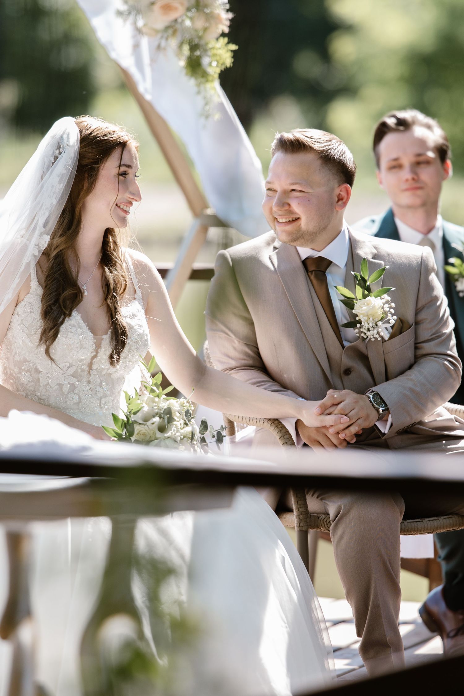 A joyful wedding ceremony moment under a floral arch in an outdoor garden setting.