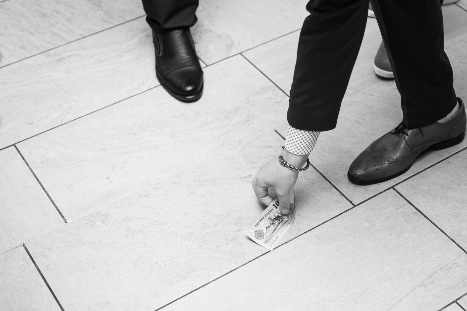 Close-up of formal shoes and feet on white dance floor during wedding reception.