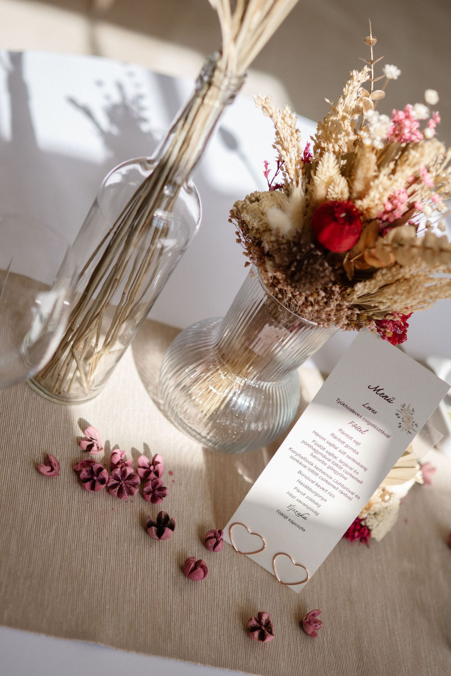 Wedding reception table setting with dried floral arrangements and a menu card decorated with hearts.