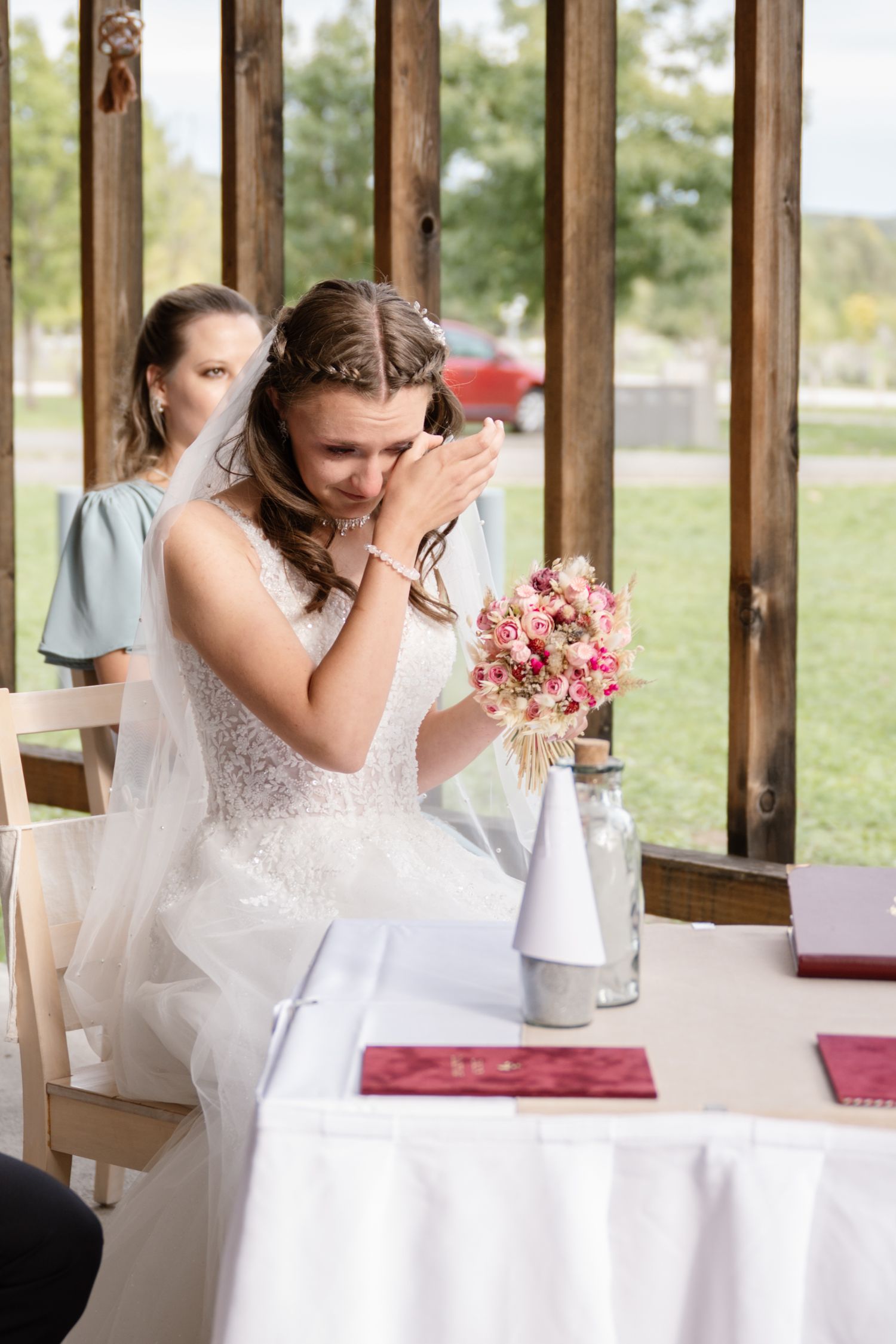 Emotional moment at a rustic wedding reception with white tablecloths and floral centerpieces.