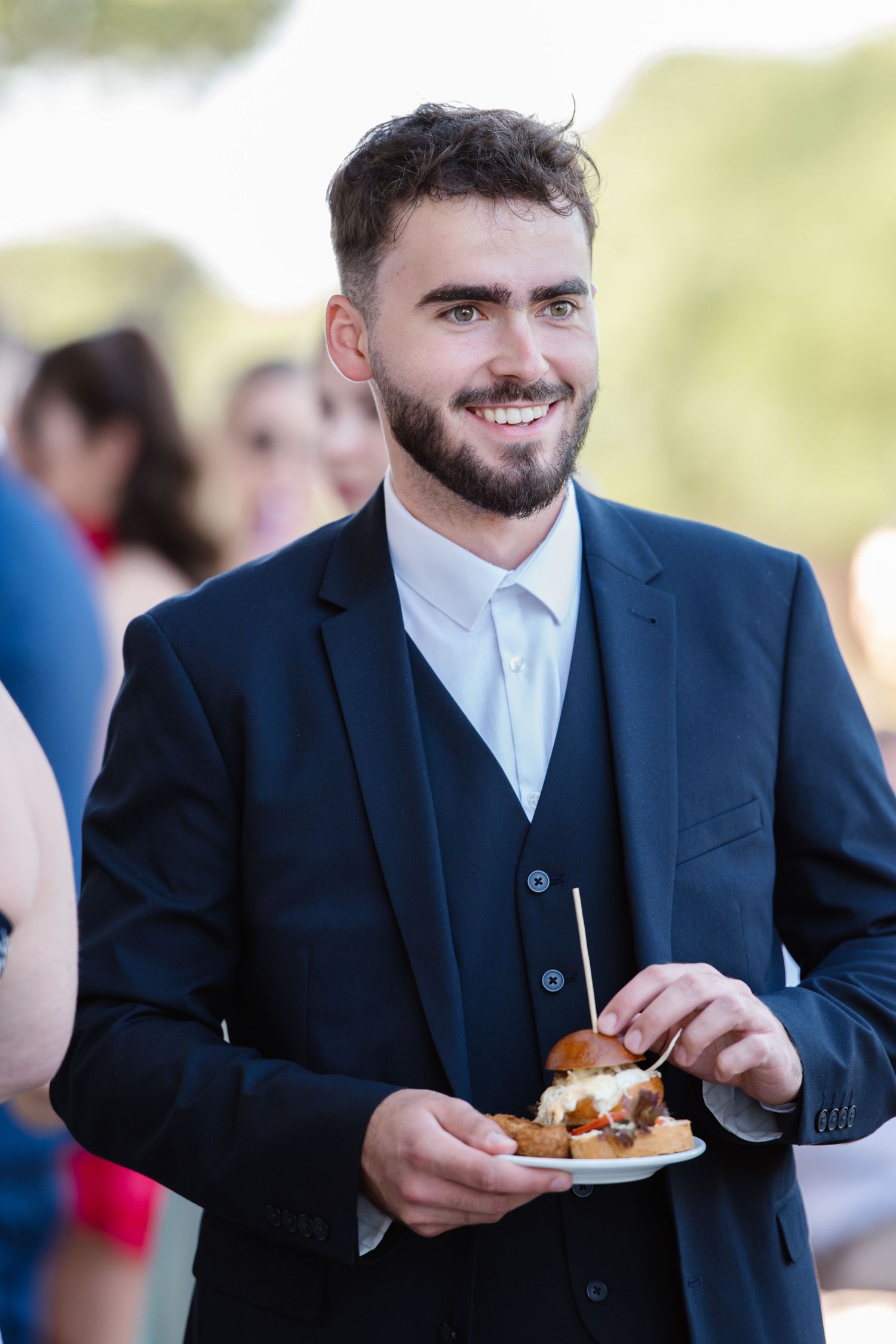 Guest in navy suit enjoying appetizers at wedding reception.