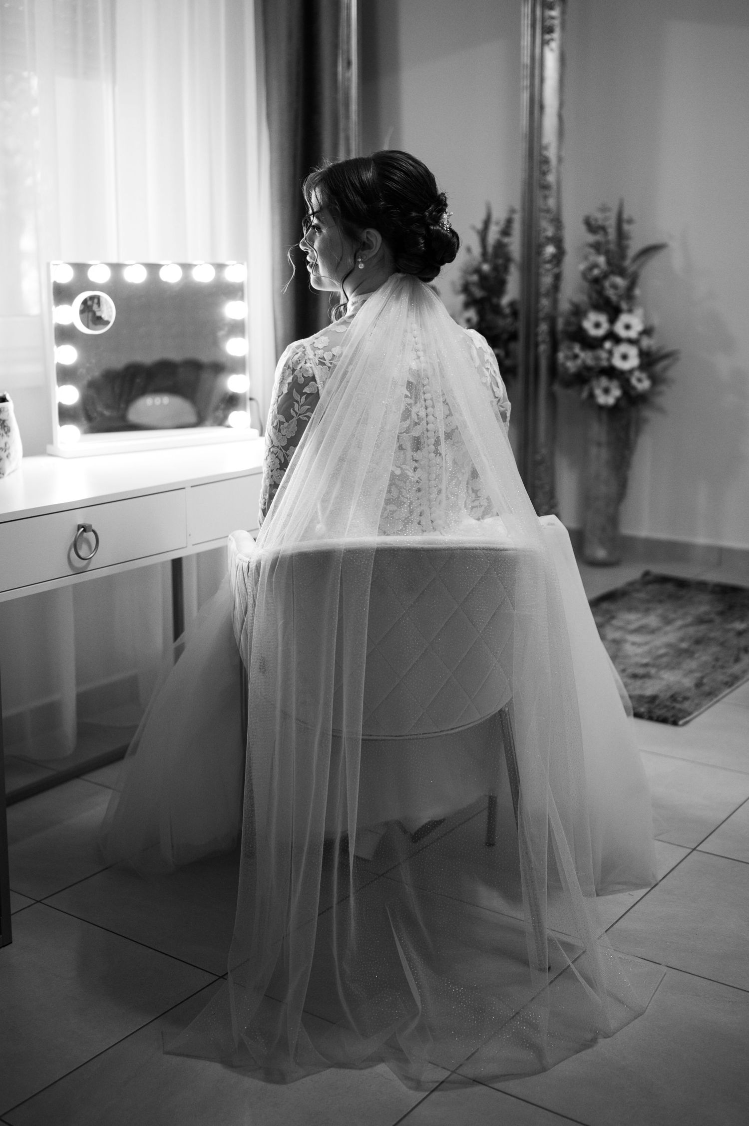 Black and white photo of a bride's wedding dress and veil in a dressing room.
