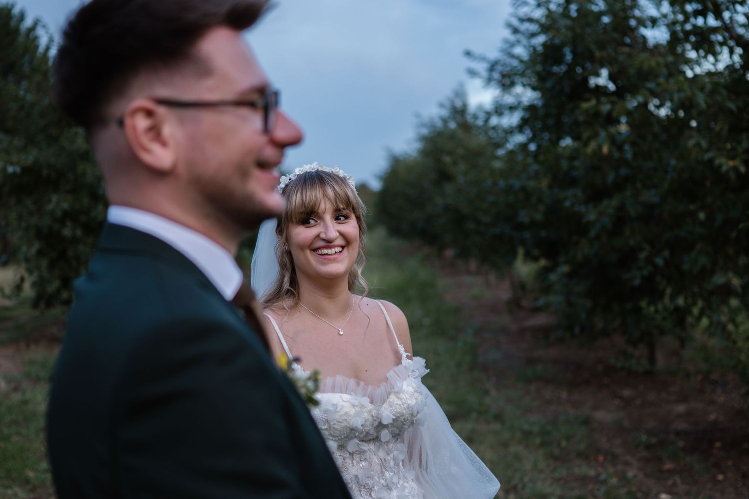 Candid wedding photos captured in an outdoor orchard setting at dusk.