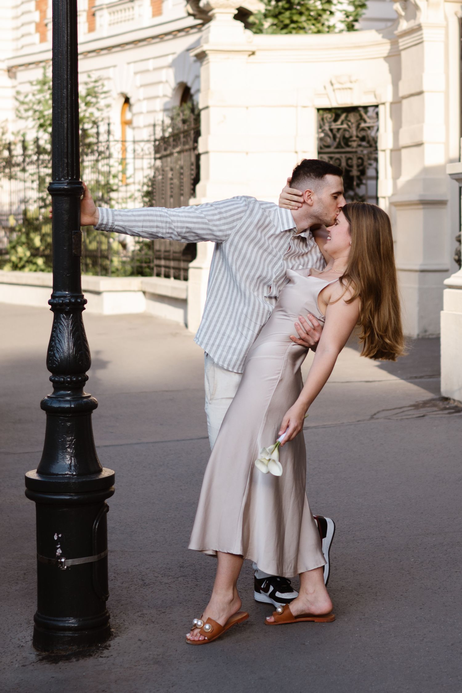 Romantic couple dancing together on a city sidewalk near a vintage lamppost.