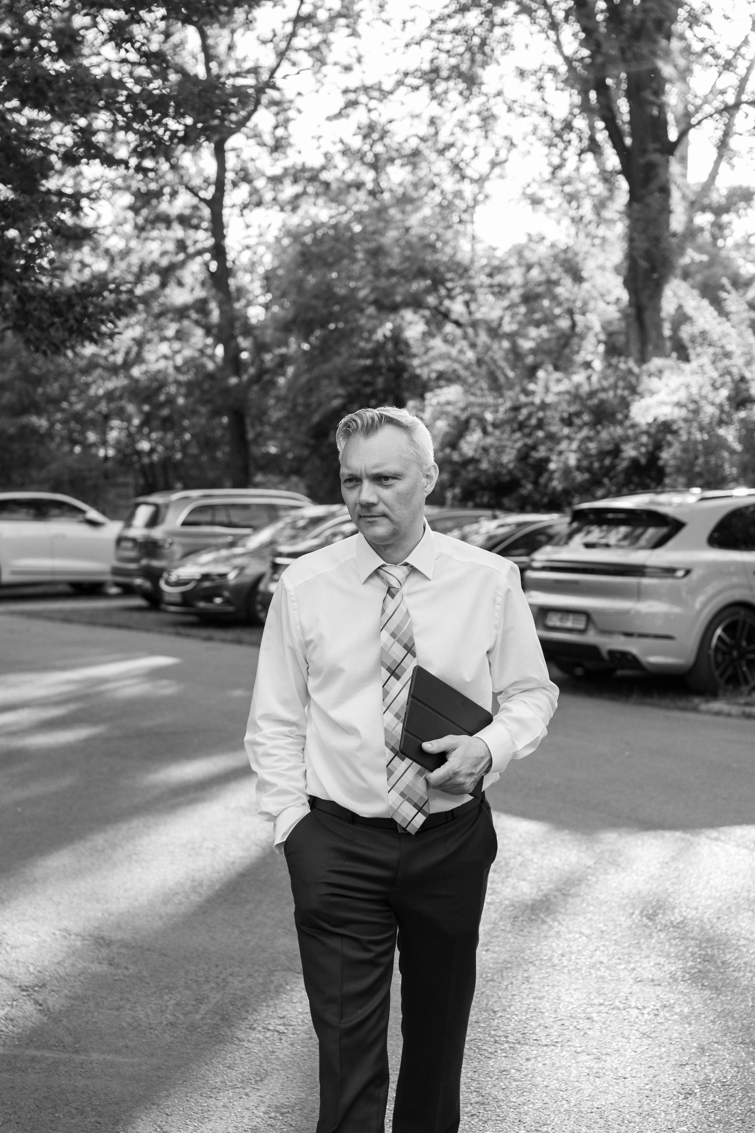 Person in formal attire adjusting their tie in a parking lot.