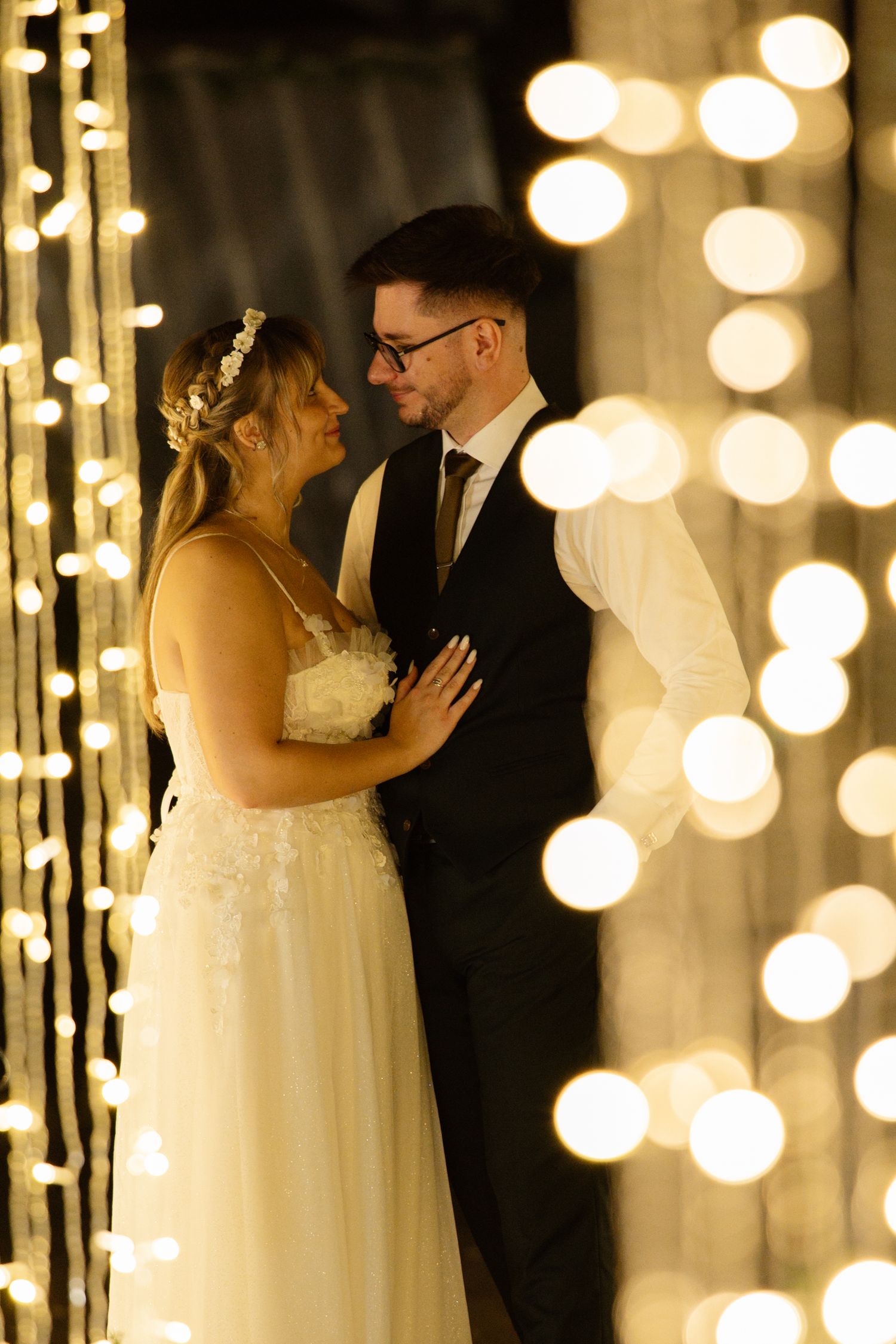 Romantic wedding couple silhouettes against glowing string light backdrop.