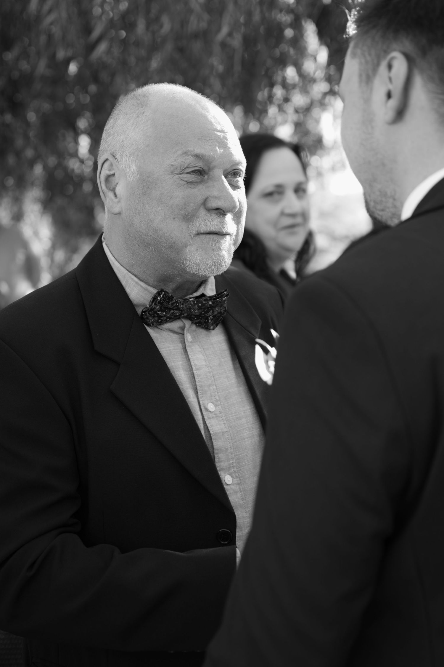 Black and white candid shots of wedding guests during an outdoor celebration.