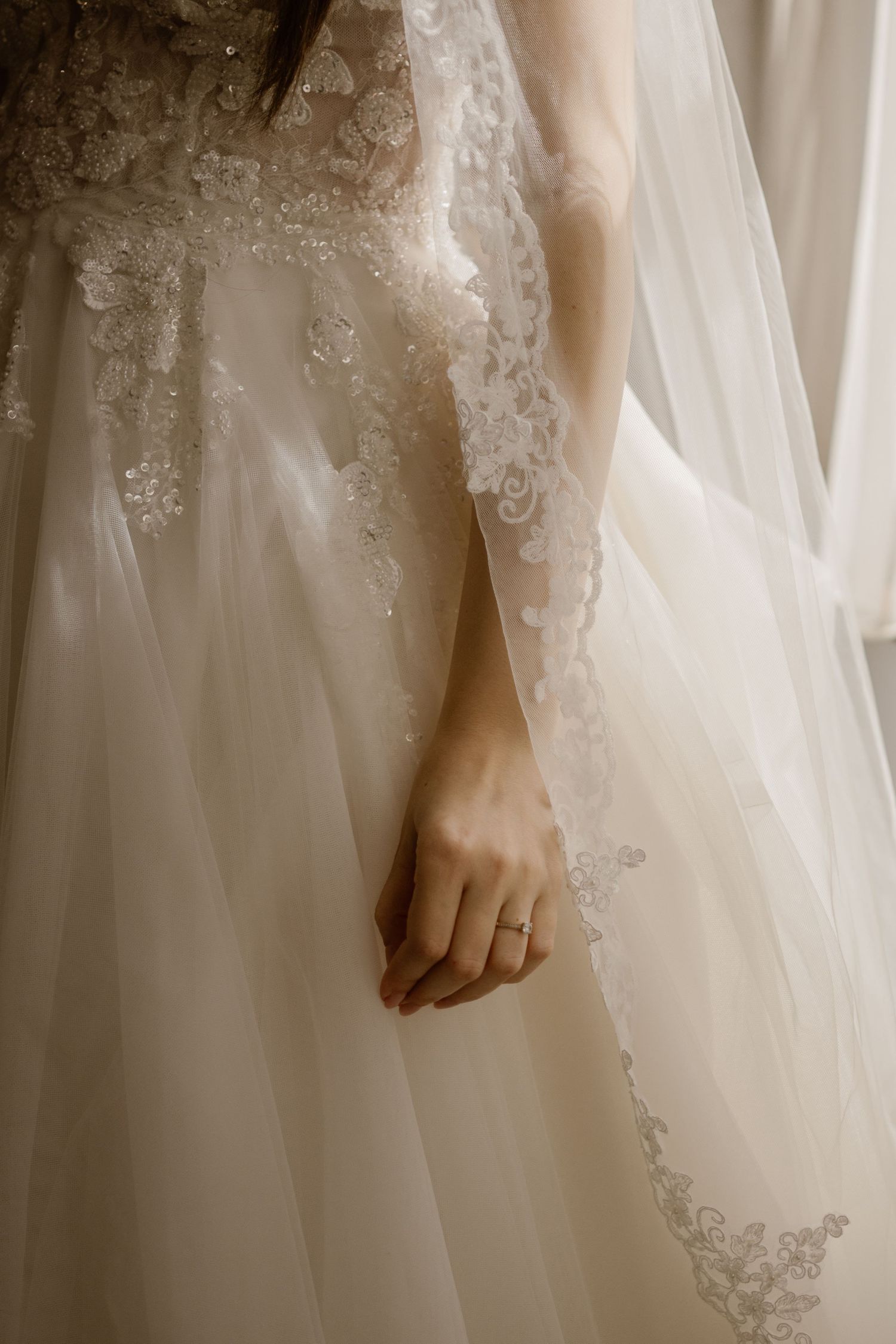 Delicate lace details and fabric drape elegantly on a white wedding dress.