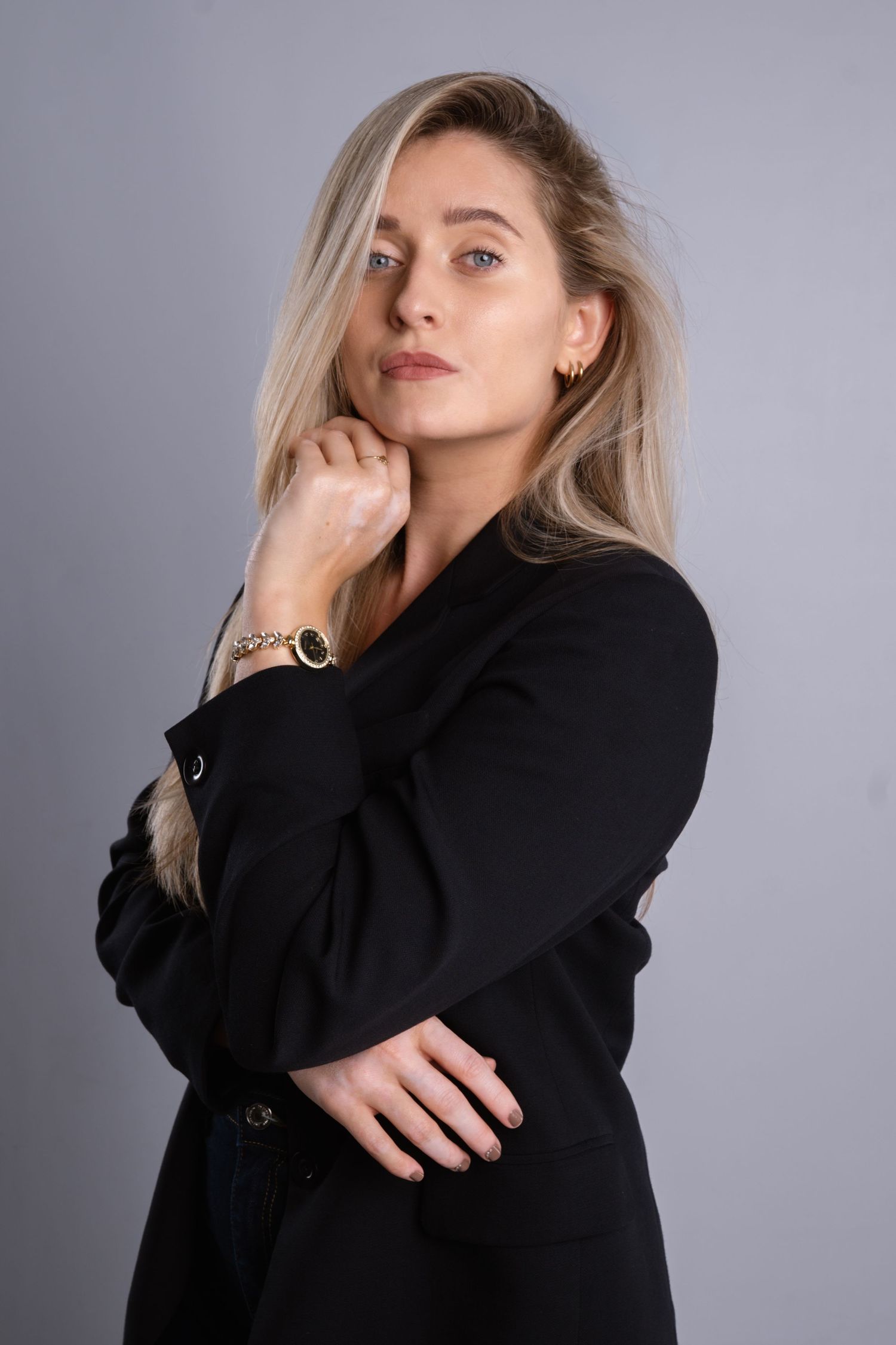 Studio fashion shoot featuring black blazer and elegant poses on grey background.