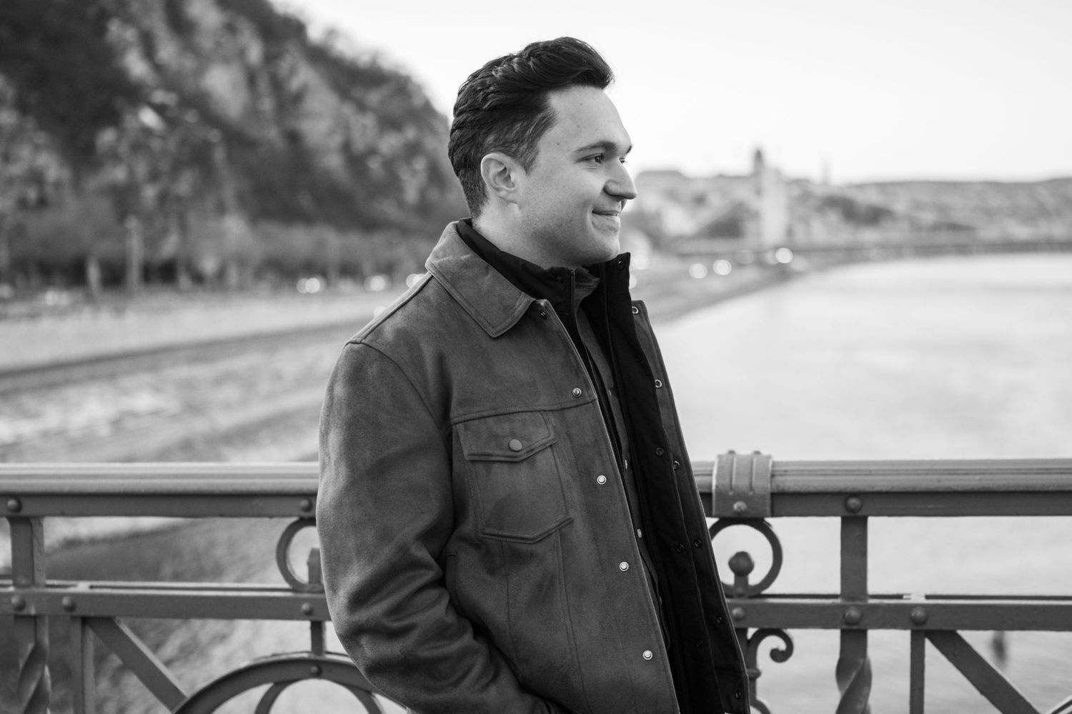 Professional outdoor portrait session featuring brown leather jacket against scenic waterfront backdrop.