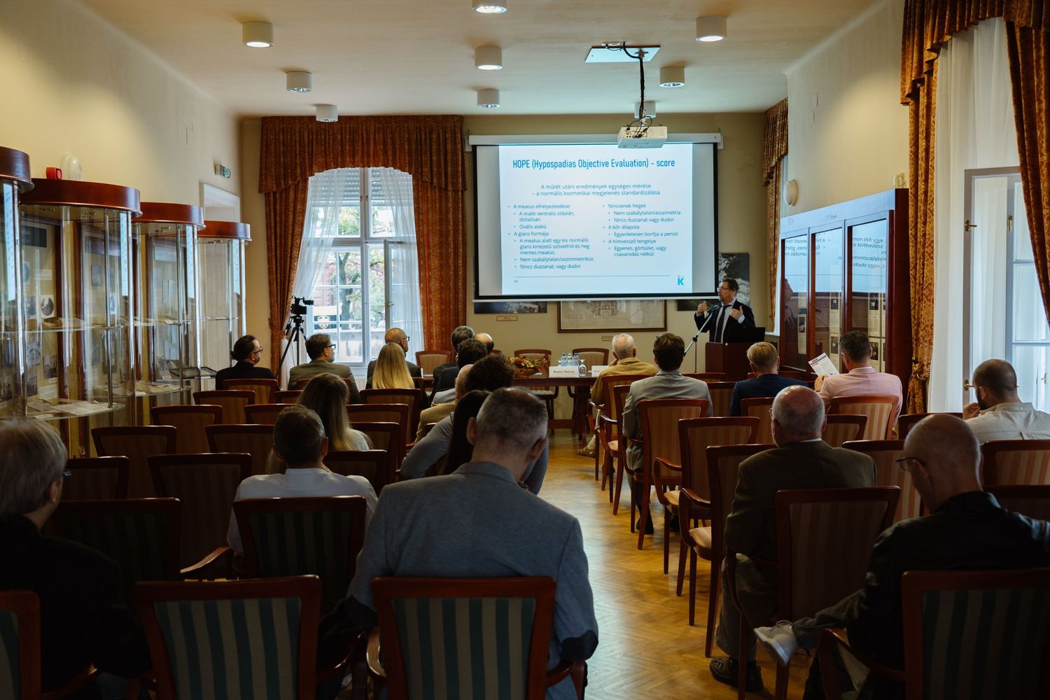 Business conference room with projector screen and rows of chairs showing presentation slides.