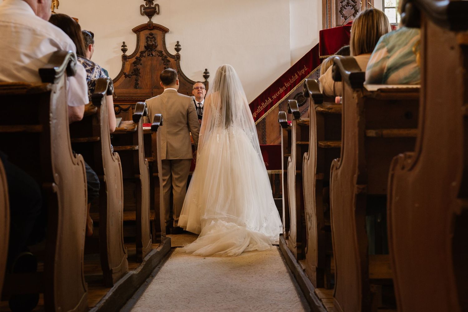 Church aisle lined with wooden pews during a wedding ceremony.