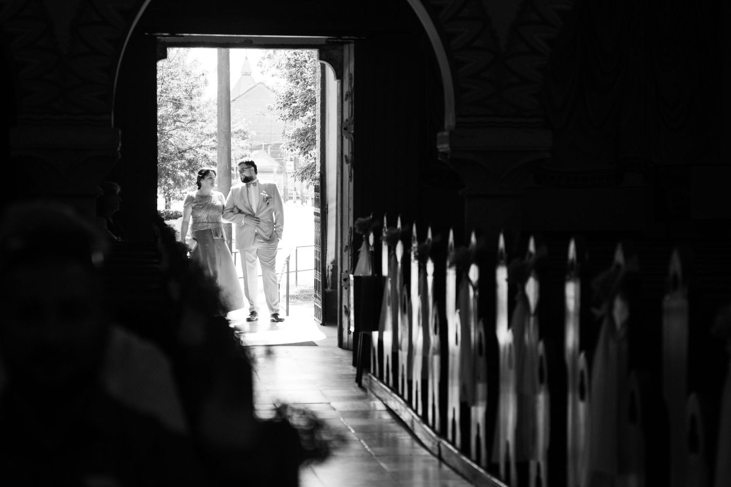 Dark silhouette of church pews in a dramatic black and white photograph.